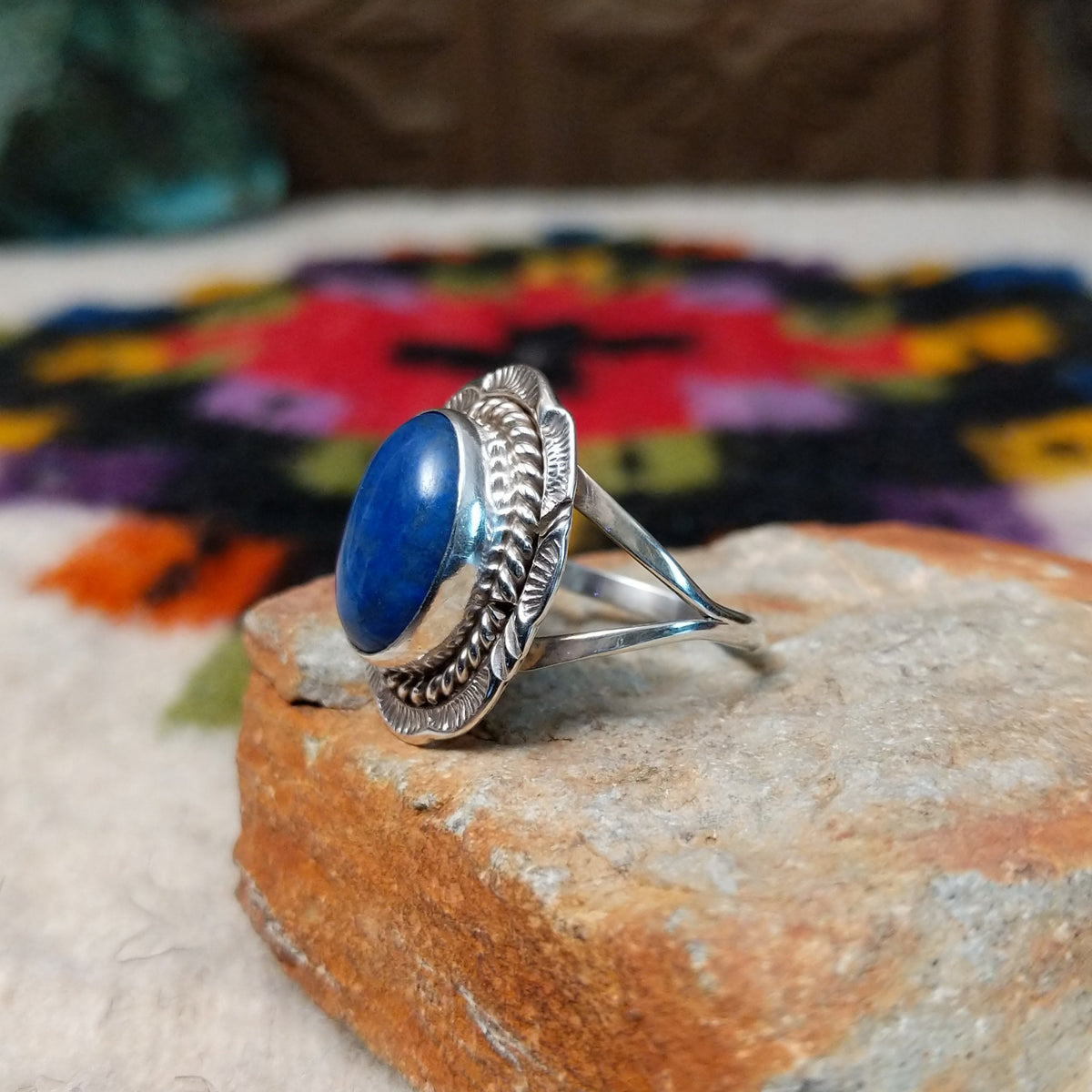Navajo lapis ring by P. with oval blue stone, twisted silver border, and stamped details.