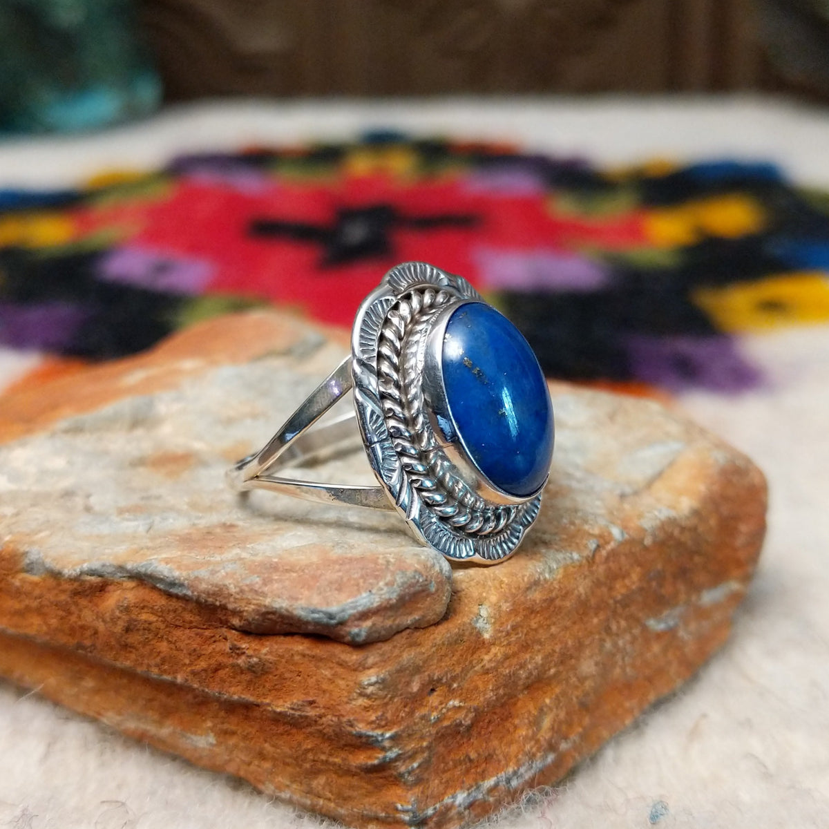 Navajo lapis ring by P. with oval blue stone, twisted silver border, and stamped details.