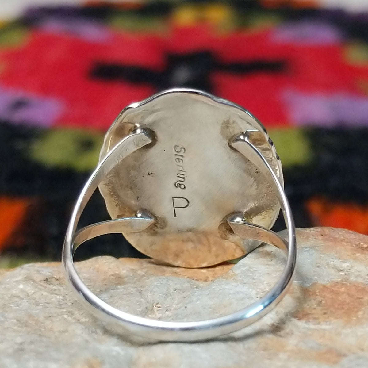 Navajo lapis ring by P. with oval blue stone, twisted silver border, and stamped details.Close up of the artist's stamped signature.