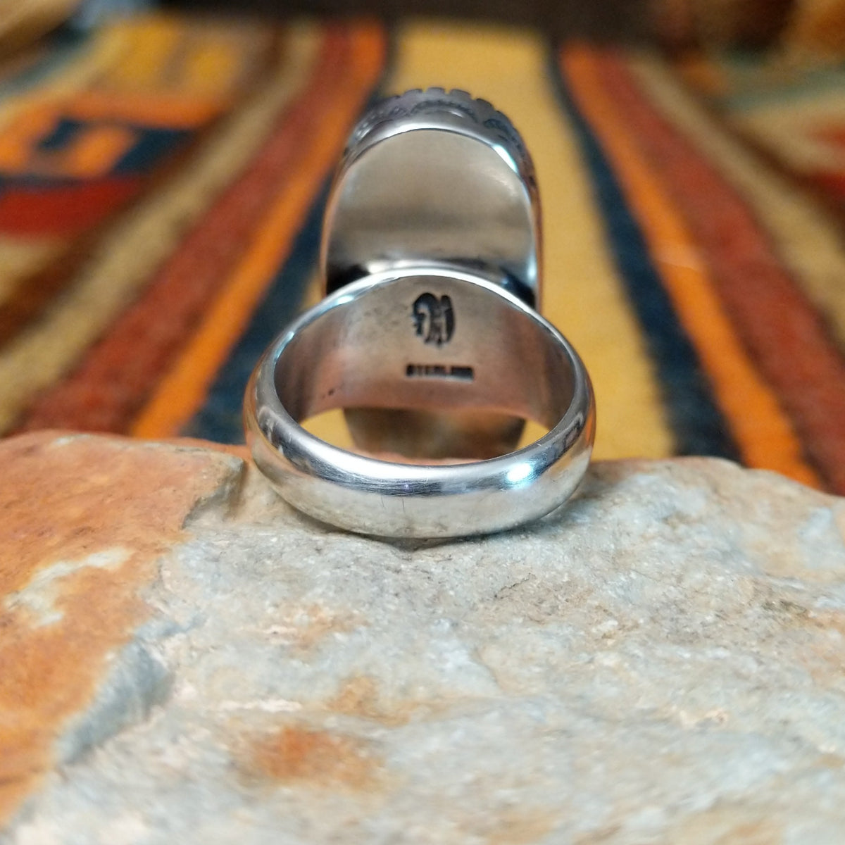 Navajo Large White Buffalo Ring featuring an elongated oval white stone with bold black matrix patterns, surrounded by a decorative notched silver bezel in a classic Southwestern statement design; underside view.