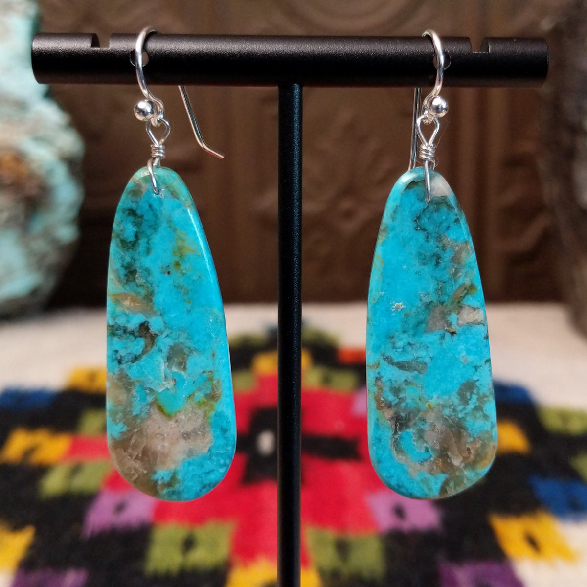 Navajo Long Oval Slab Turquoise Earrings featuring elongated bright blue turquoise stones with natural brown, gray, and green matrix, suspended from silver hooks.