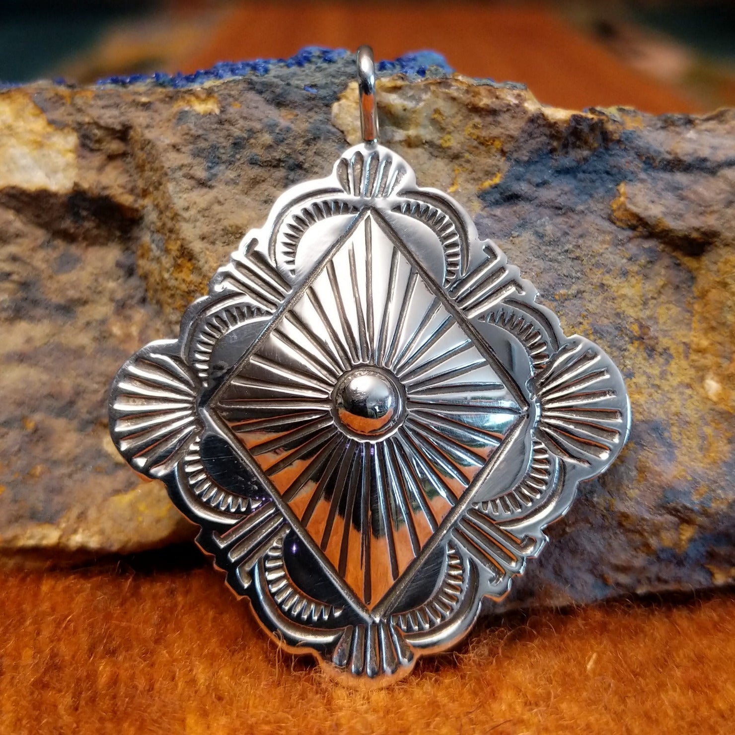 Diamond shaped sterling silver pendant with sun ray motif.