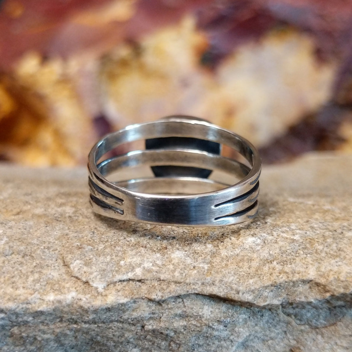 The sterling silver tri-band tapers toward the center.