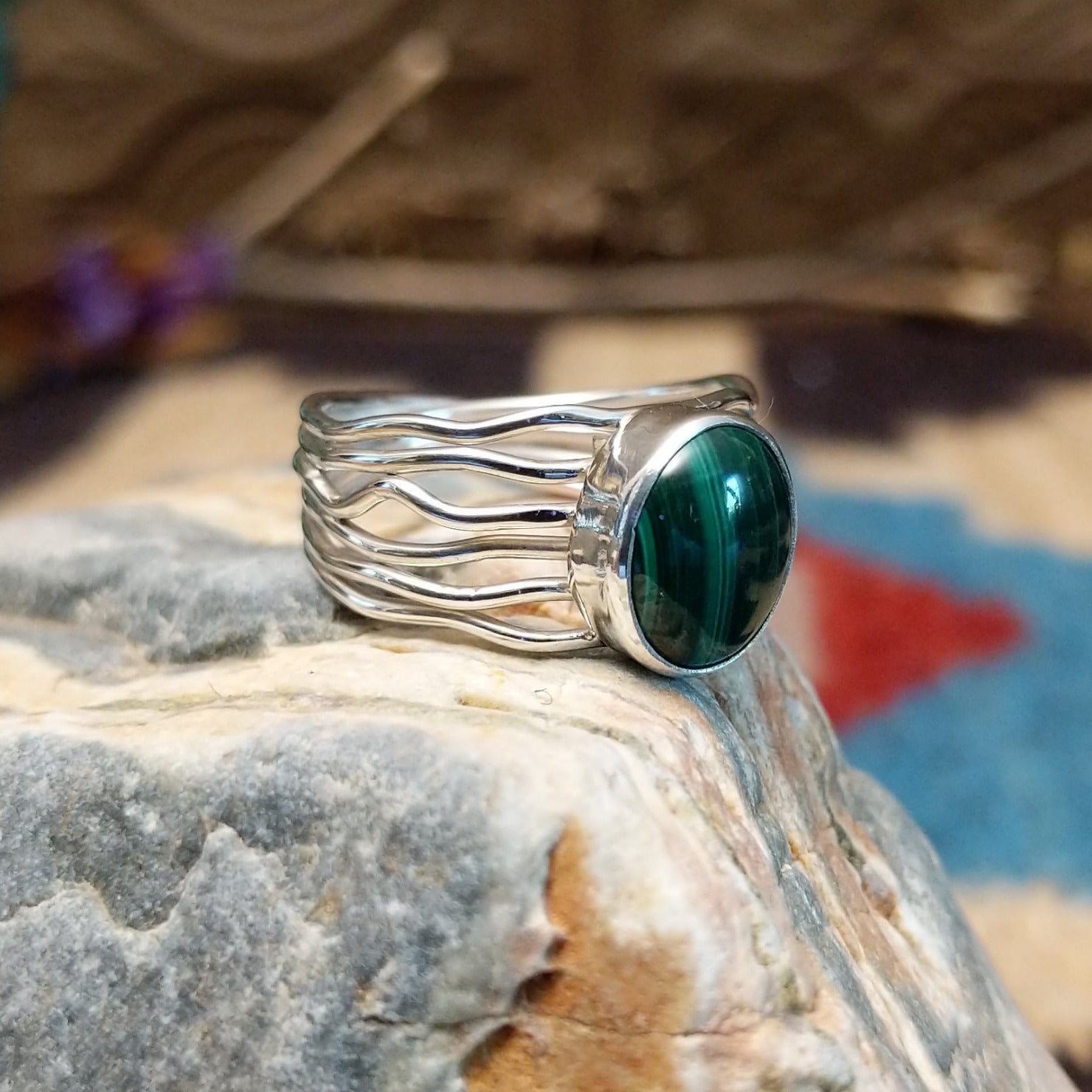 Sterling silver ring with malachite set in the raised, round bezel and silver strands making up the band.