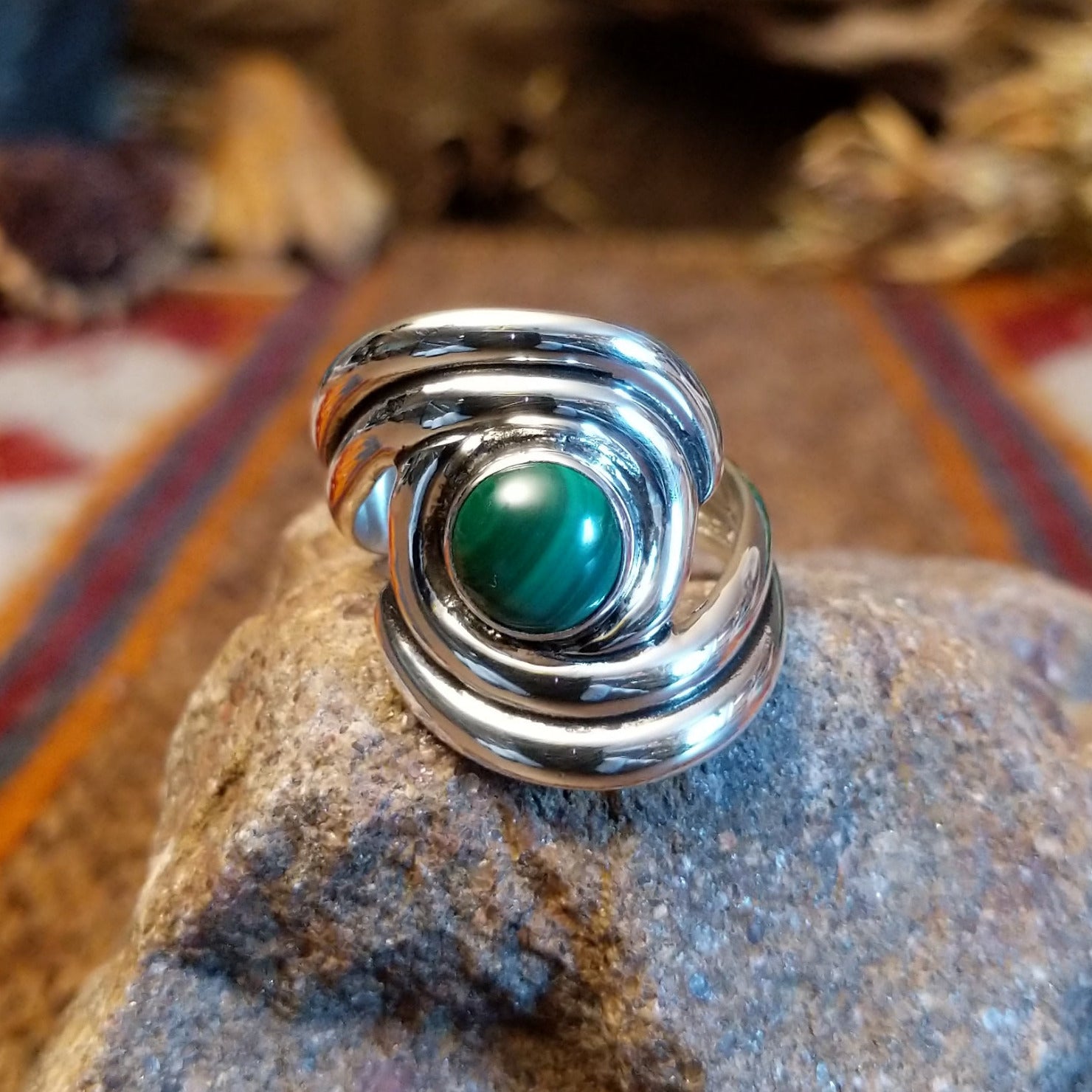 Sterling silver ring with malachite set in the bezel and framed by swirling silverwork.