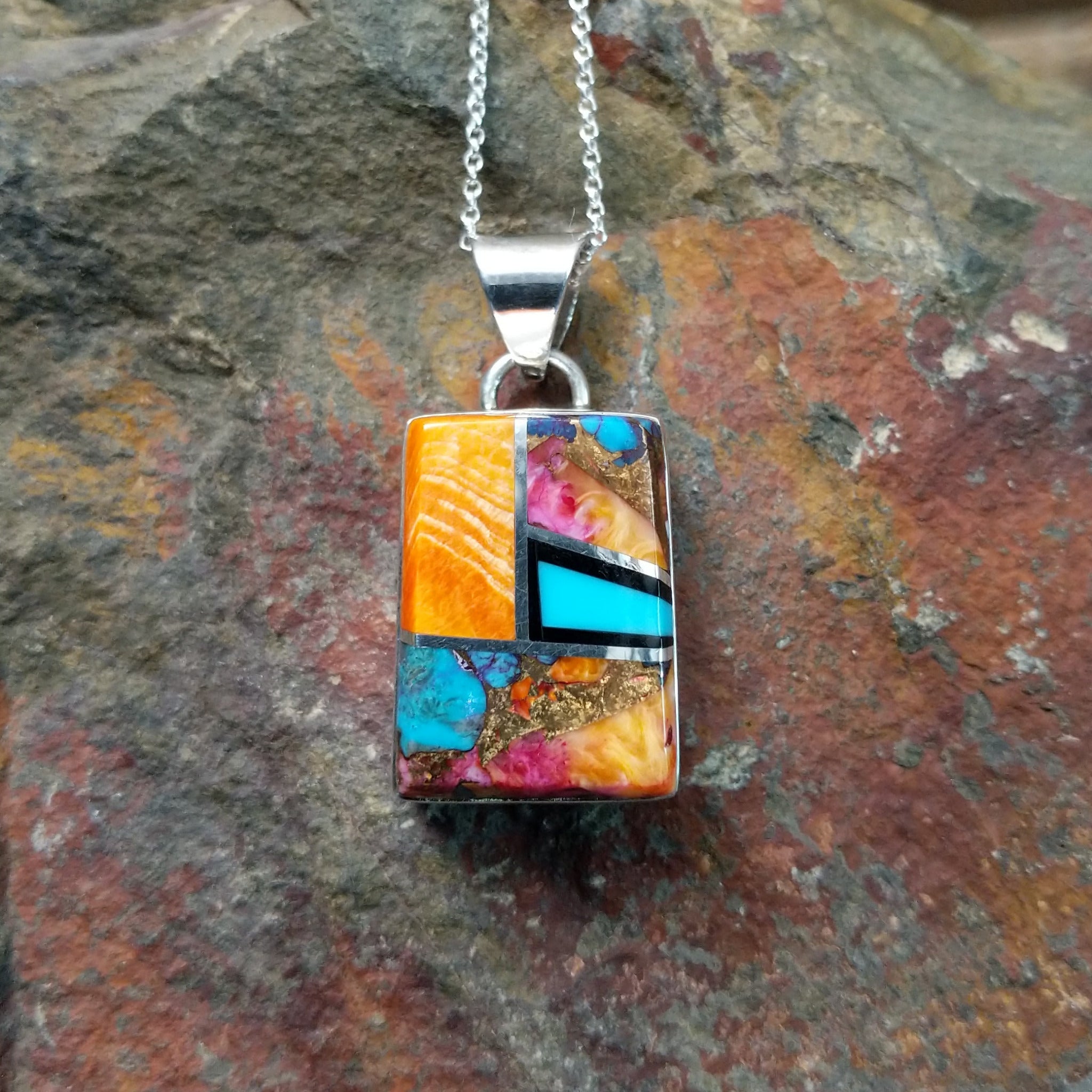 Handcrafted sterling silver compressed stone inlay pendant by S.L., featuring a colorful geometric Navajo design.
