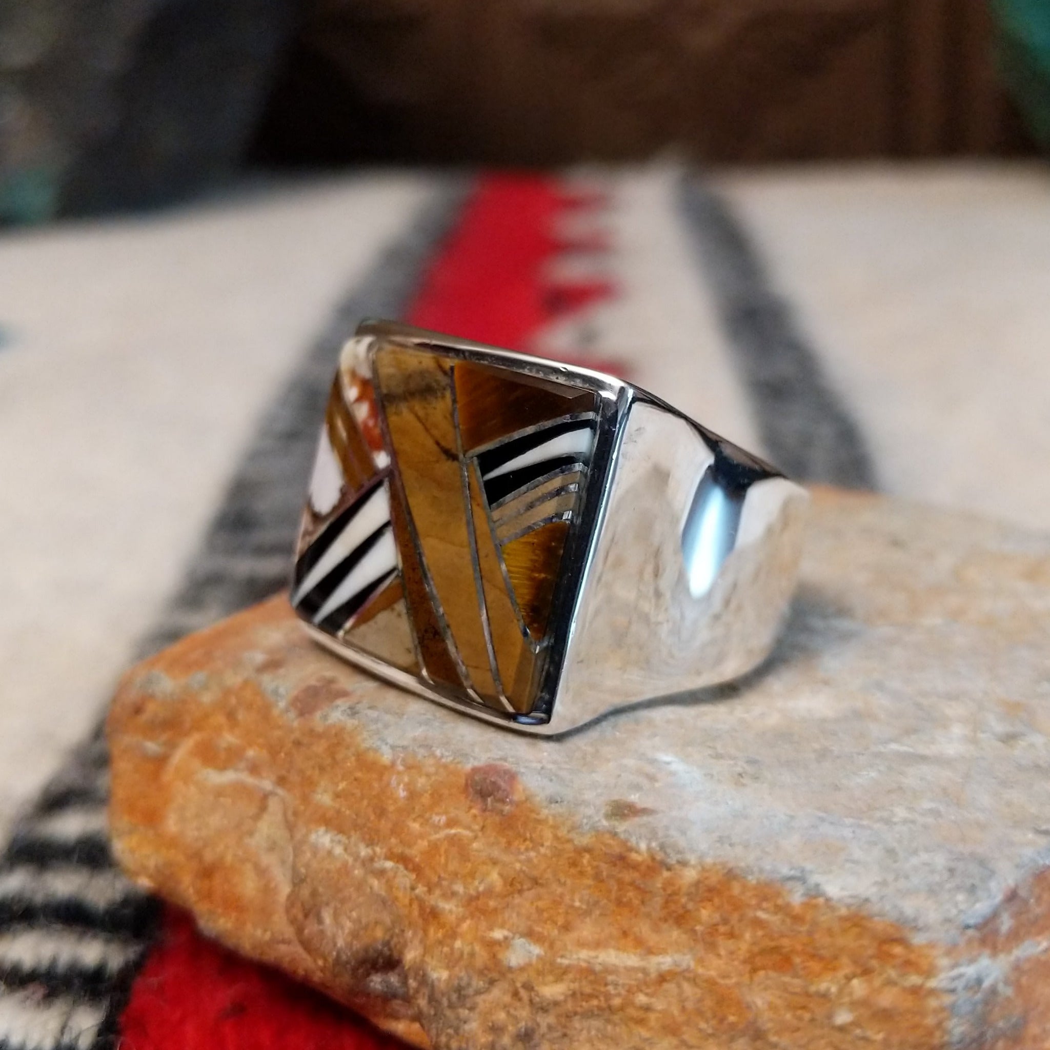 Navajo multistone inlay ring by B.J. with a square geometric design in brown, tan, black, and white stones separated by fine silver channels and set in polished silver; side view.