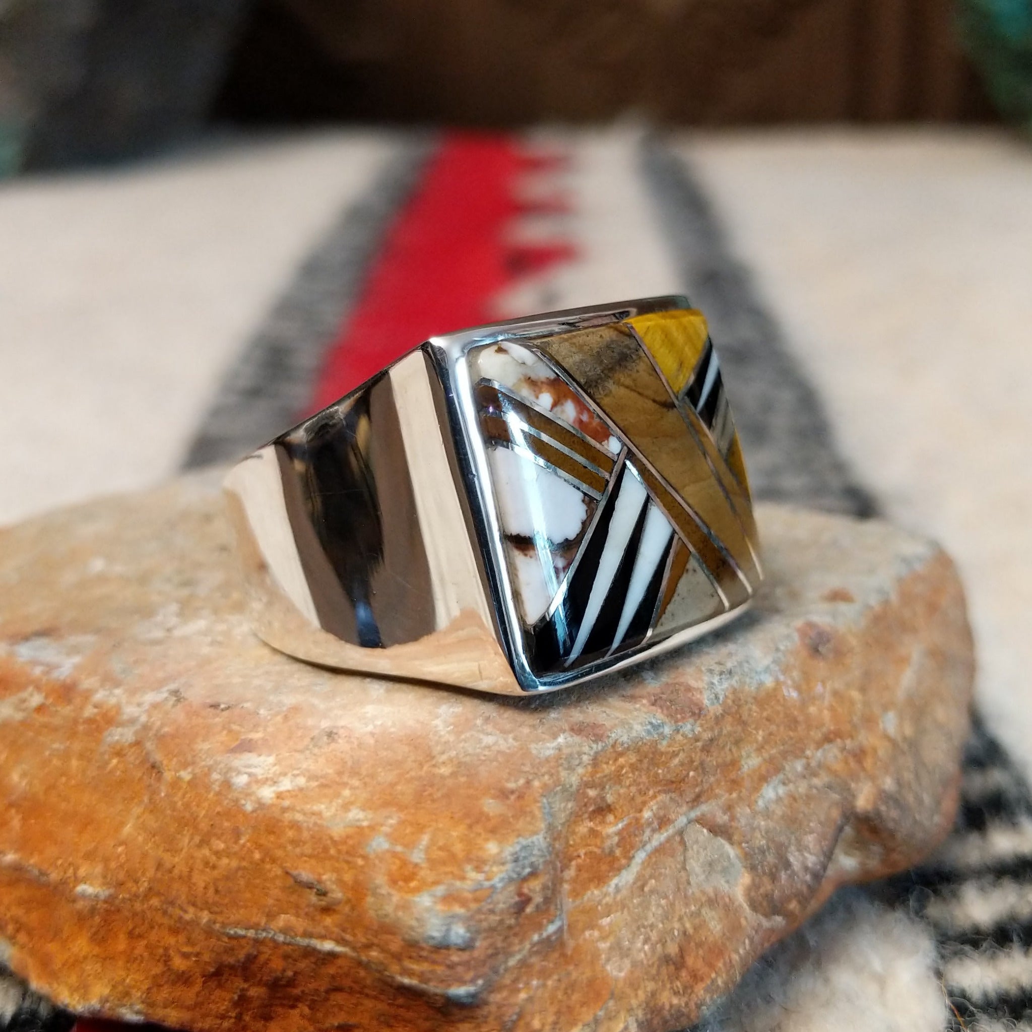 Navajo multistone inlay ring by B.J. with a square geometric design in brown, tan, black, and white stones separated by fine silver channels and set in polished silver; side view.