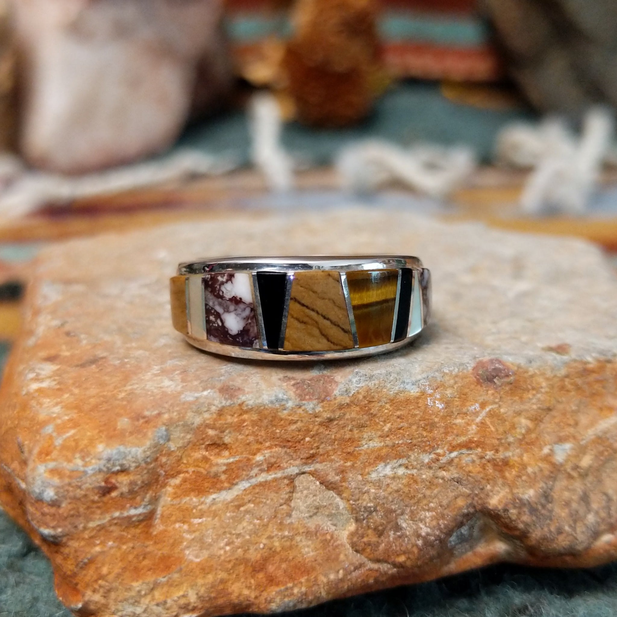 Navajo sterling silver ring by J.C. featuring geometric multistone inlay with black onyx, tiger’s eye, and assorted natural stones separated by silver dividers.