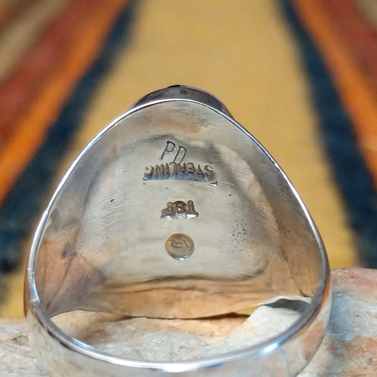 Navajo Multistone Inlay Ring by P.D. featuring an oval geometric mosaic of turquoise, black onyx, and contrasting stone inlays separated by thin silver dividers, set in a wide, polished silver band; artisan and Sterling Silver stamp.