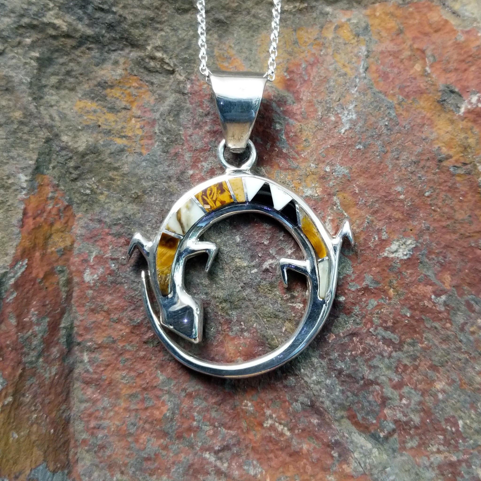 Handcrafted sterling silver multistone lizard pendant by R.I., featuring colorful inlay in a circular openwork Navajo design.