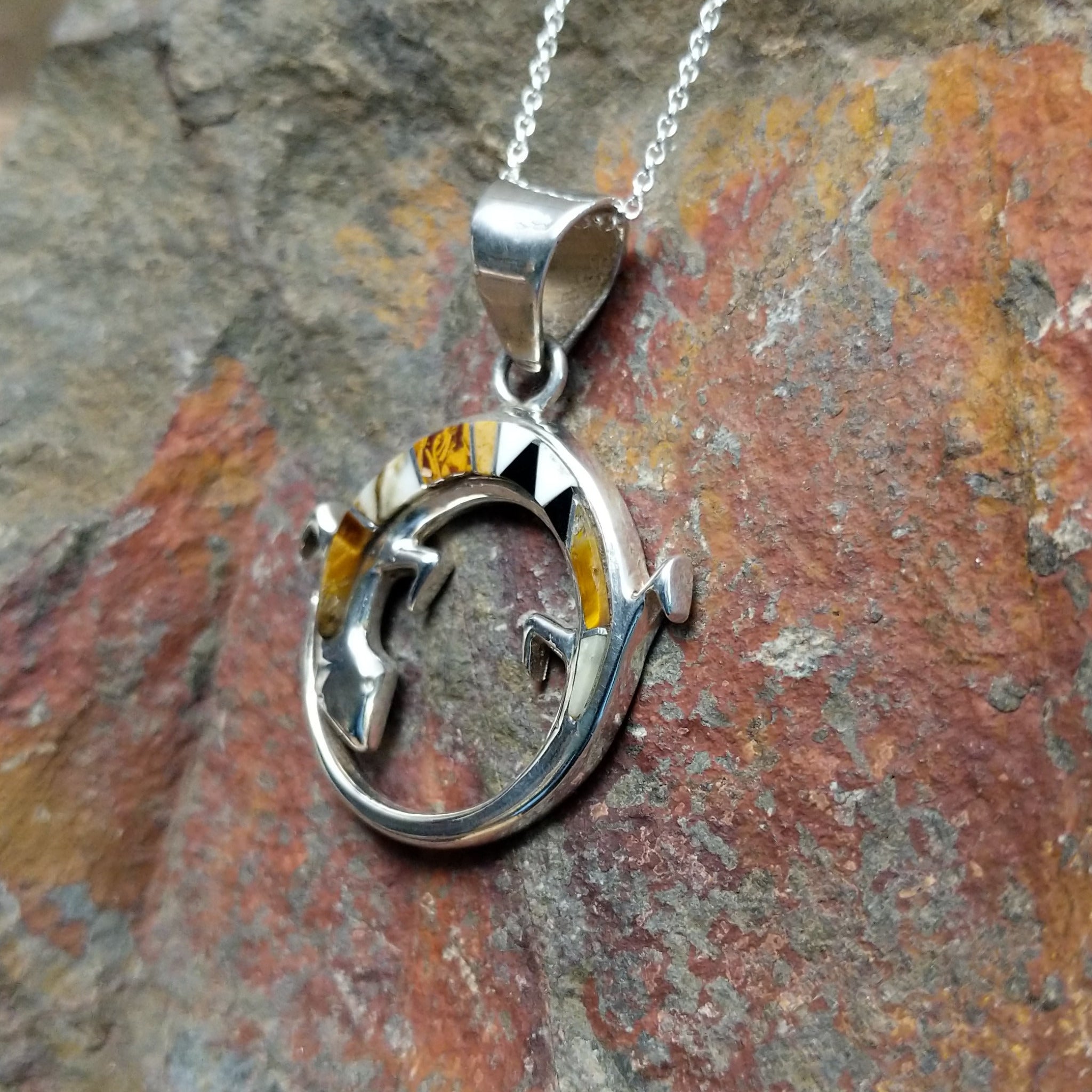 Handcrafted sterling silver multistone lizard pendant by R.I., featuring colorful inlay in a circular openwork Navajo design; side view.