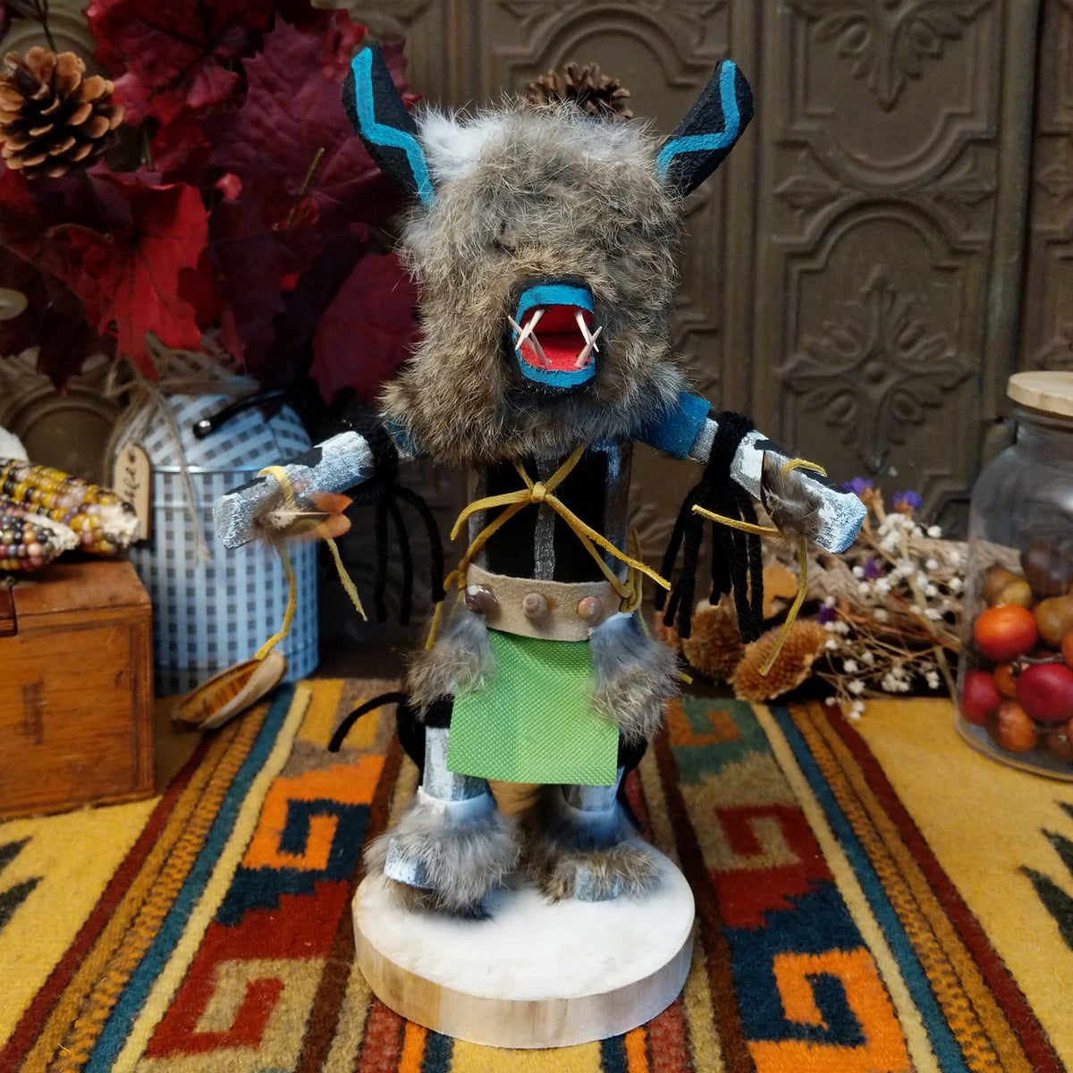Navajo Ogre Kachina doll with gray fur-covered face, black horns with turquoise markings, open red mouth, pointed teeth, and green fabric apron.