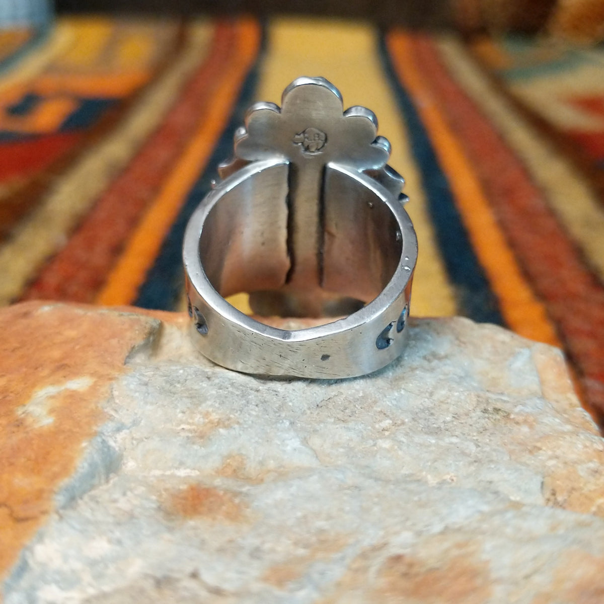 This elegant Navajo Ornate Sonoran Gold Turquoise Ring features a large oval blue turquoise stone surrounded by a silver rope border, polished silver beads, and decorative stamped silver blossoms; underside view.