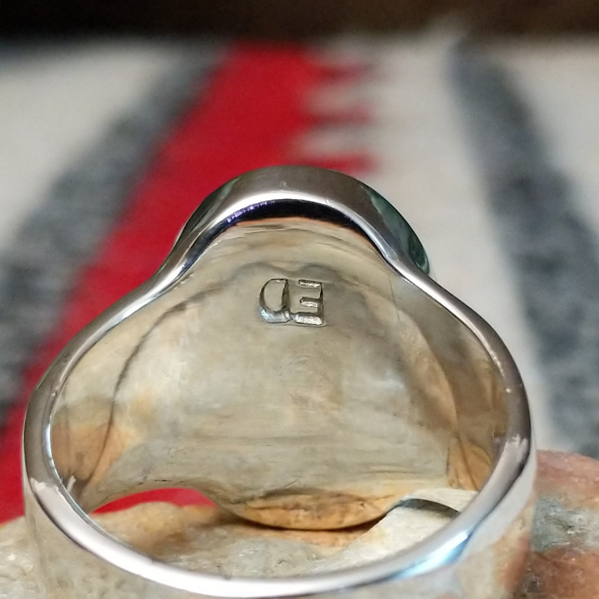 Navajo oval multistone inlay ring by E.D. featuring turquoise, blue, green, and purple stones arranged in a geometric mosaic with silver channel accents and a polished silver band; artisan stamp.