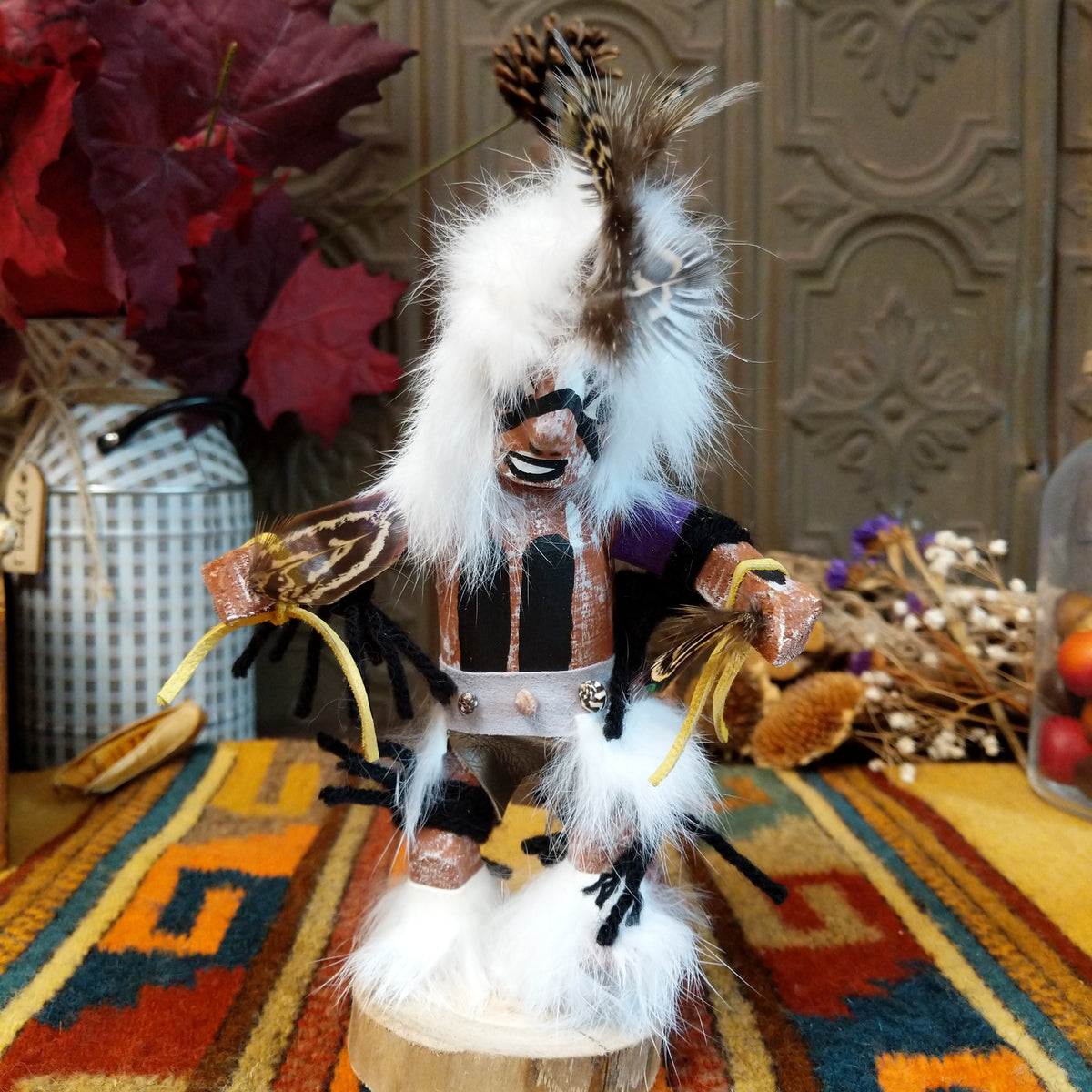 This distinctive Navajo Protection Dancer Kachina by Debbie James features a hand-painted wooden figure with a white feather headdress, natural feathers, leather ties, fur accents, colorful fabric details, and a wooden display base.