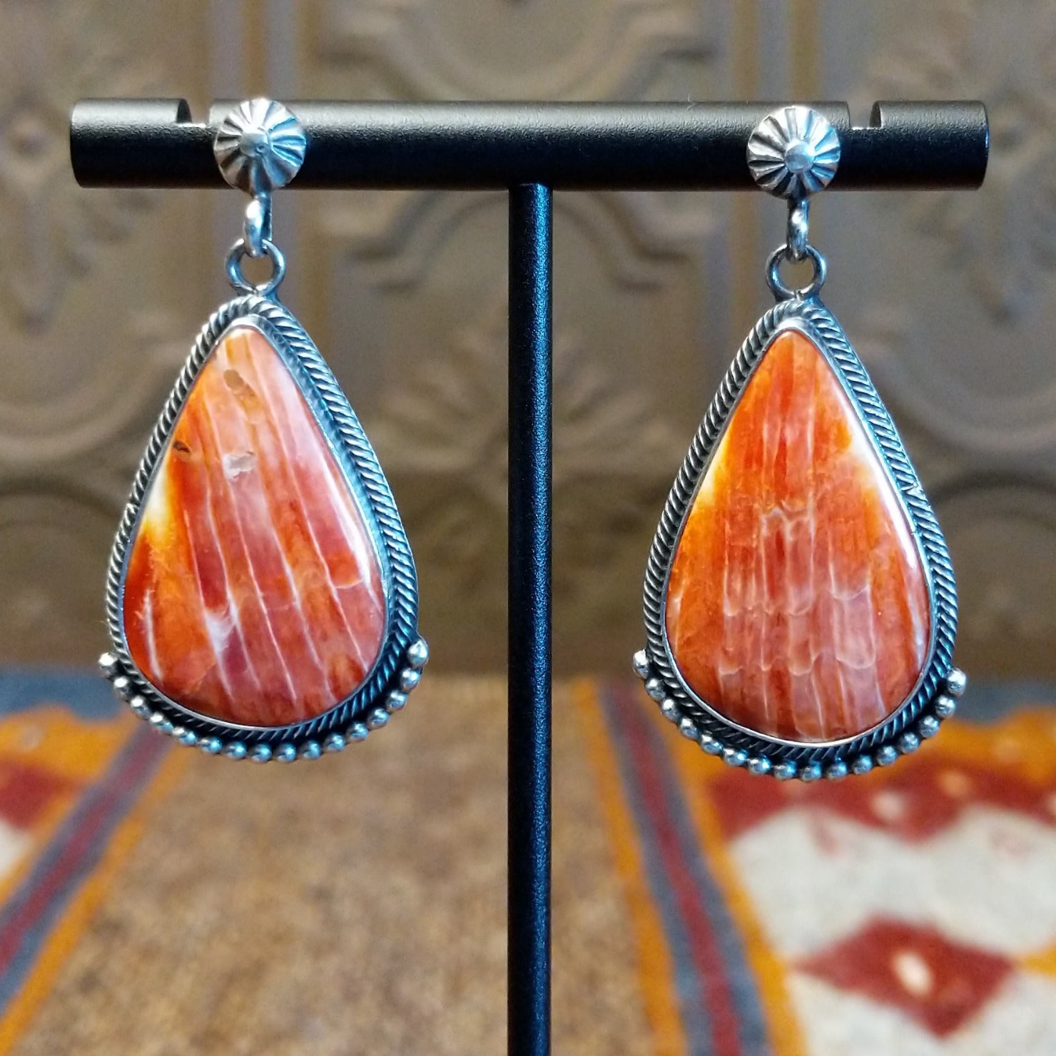Sterling silver teardrop earrings with red spiny oyster shell set in the bezels, framed by dotted accents.