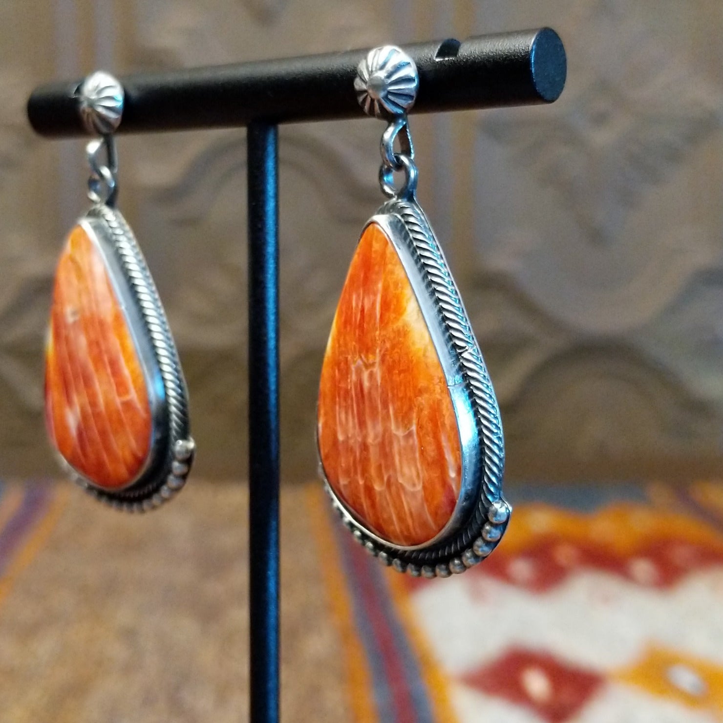 Sterling silver teardrop earrings with red spiny oyster shell set in the bezels, framed by dotted accents.