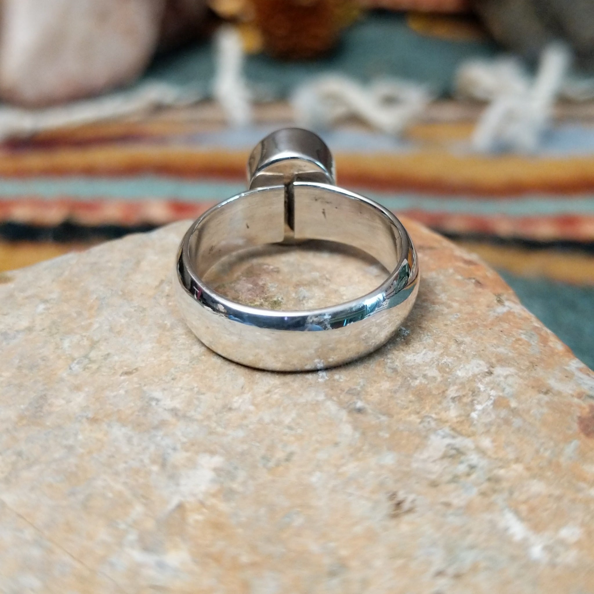 Navajo sterling silver ring by W.B.V. featuring a smooth oval red coral cabochon set in a polished silver bezel and band; underside view.