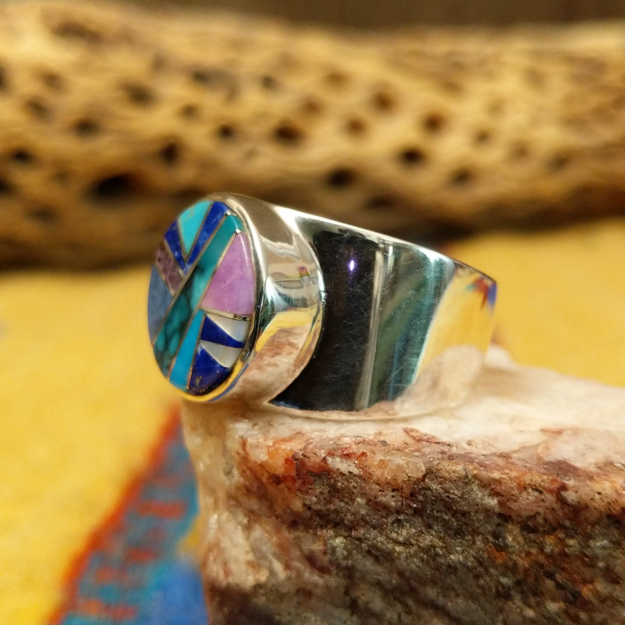 Navajo round multistone inlay ring, featuring a circular arrangement of natural stones set in a handcrafted sterling silver band with traditional Southwestern-inspired craftsmanship. Side view.