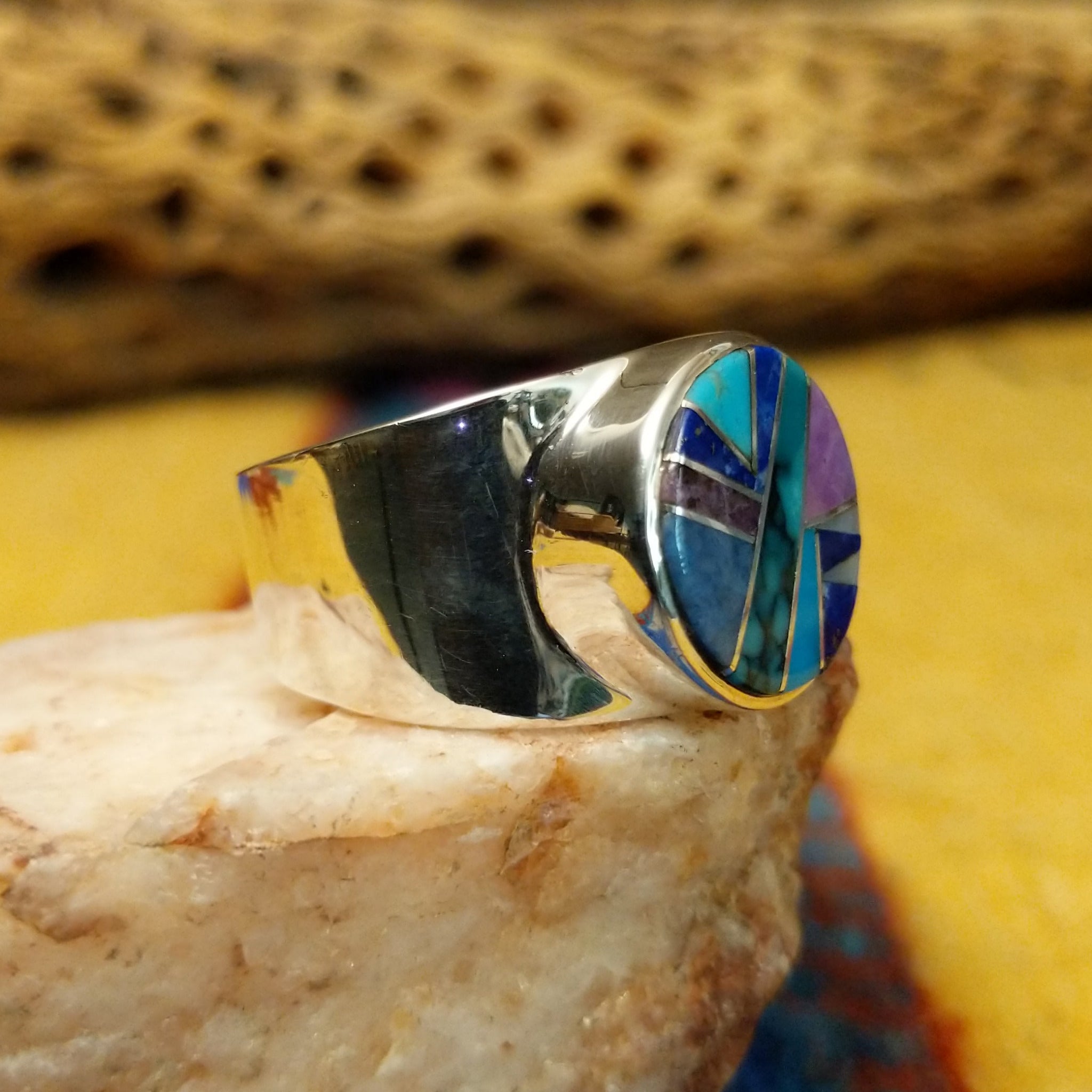 Navajo round multistone inlay ring, featuring a circular arrangement of natural stones set in a handcrafted sterling silver band with traditional Southwestern-inspired craftsmanship. Side view.