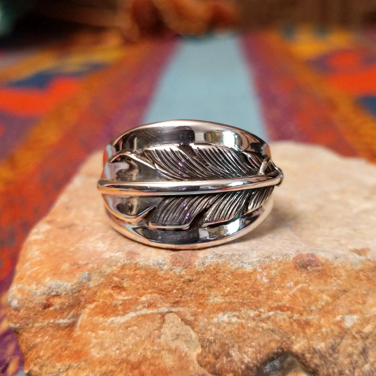 Navajo Silver Feather Ring by L.P. featuring a detailed engraved feather with a raised curved quill across a wide, polished silver band.