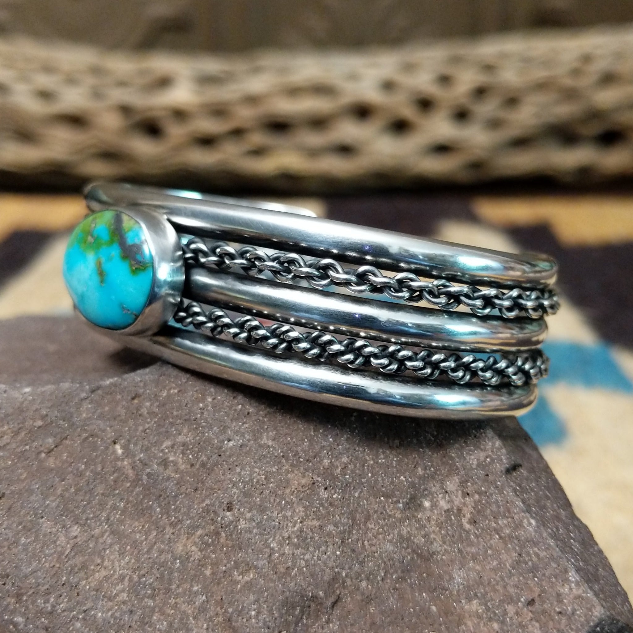 Navajo Sonoran Gold turquoise cuff by H.R.M., featuring an oval blue and green Sonoran Gold turquoise stone with natural matrix set in a handcrafted sterling silver cuff with twisted chain accents; side view.