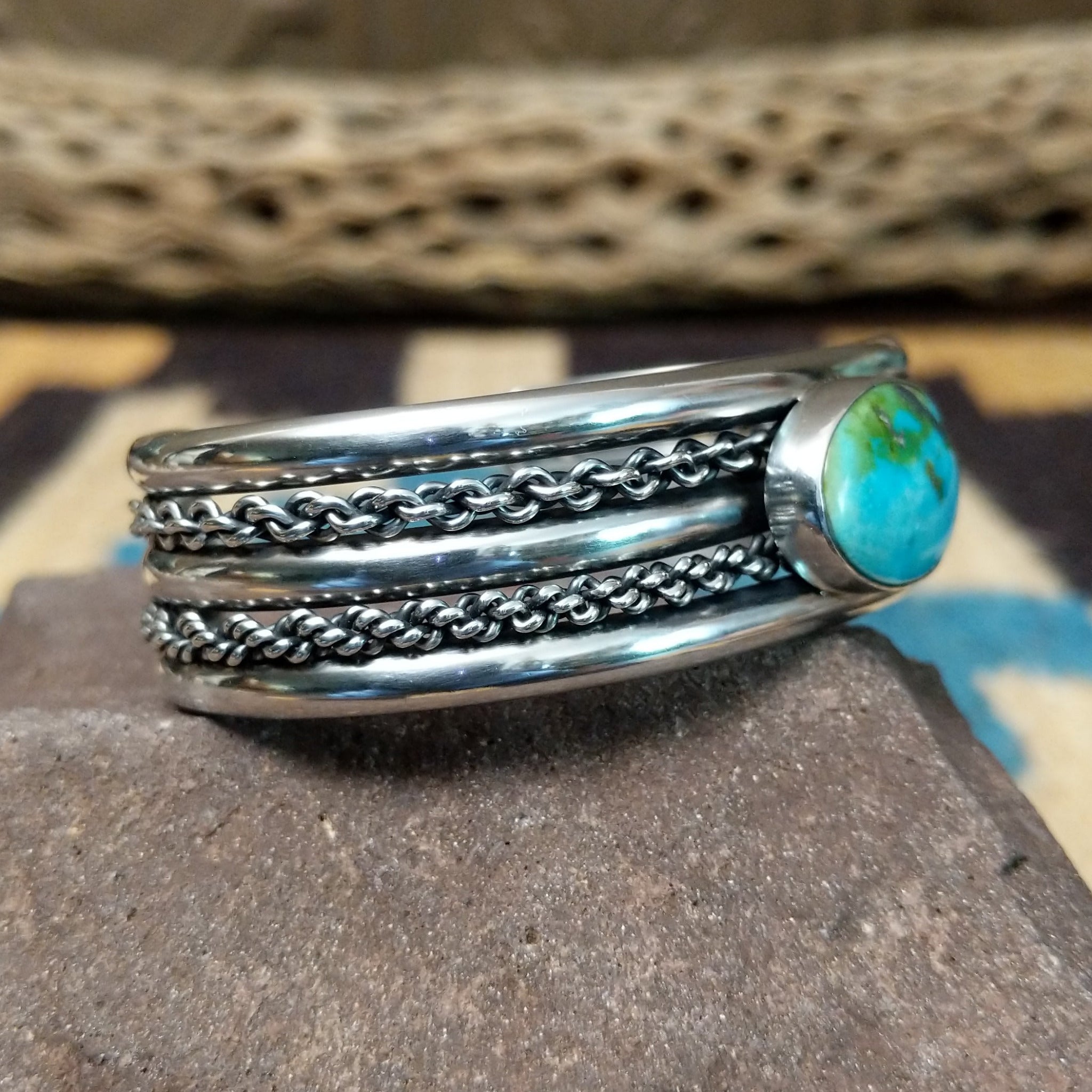 Navajo Sonoran Gold turquoise cuff by H.R.M., featuring an oval blue and green Sonoran Gold turquoise stone with natural matrix set in a handcrafted sterling silver cuff with twisted chain accents; side view.