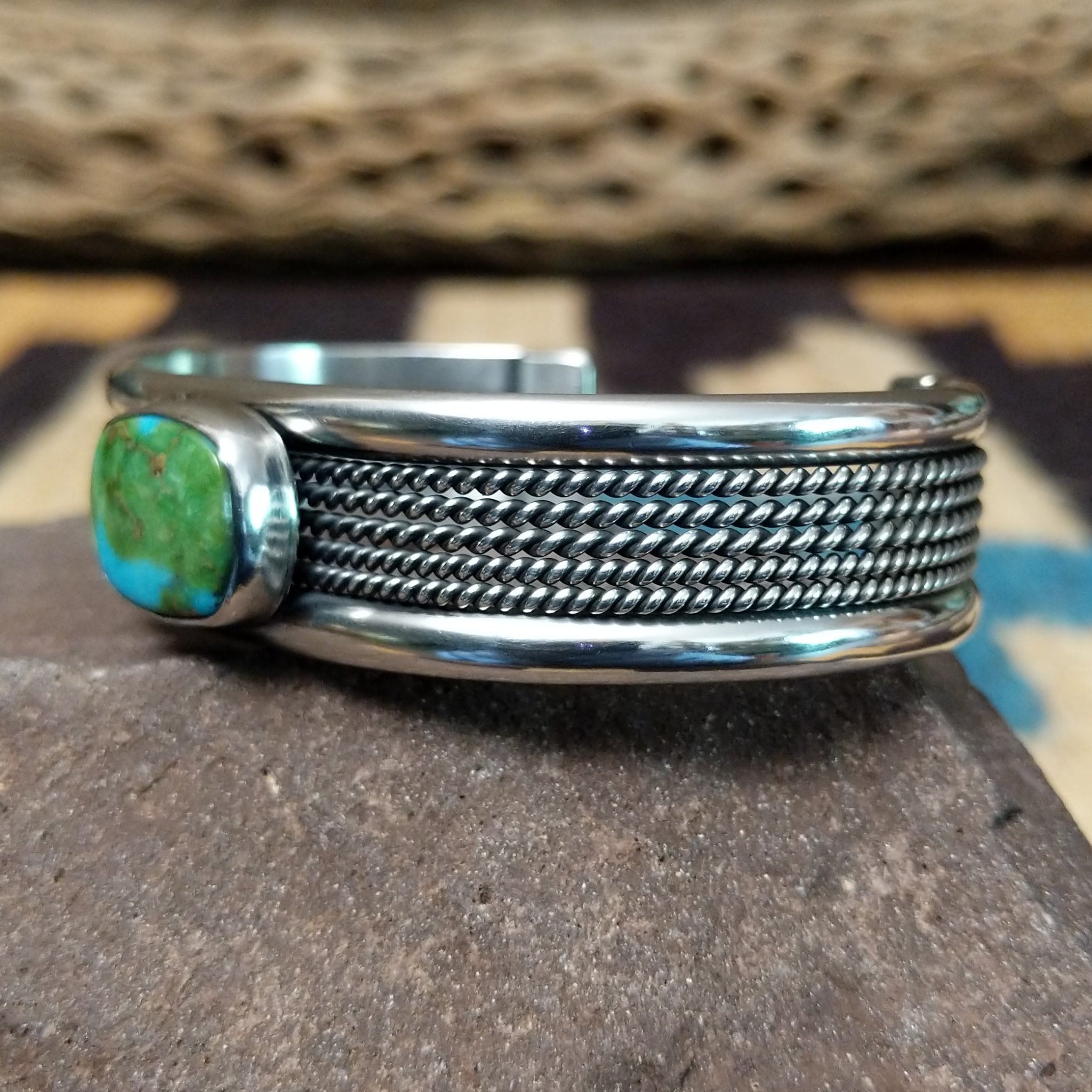 Navajo Sonoran Gold turquoise cuff by H.R.M. with a natural blue-green turquoise stone on a triple-shank sterling silver cuff; side view.