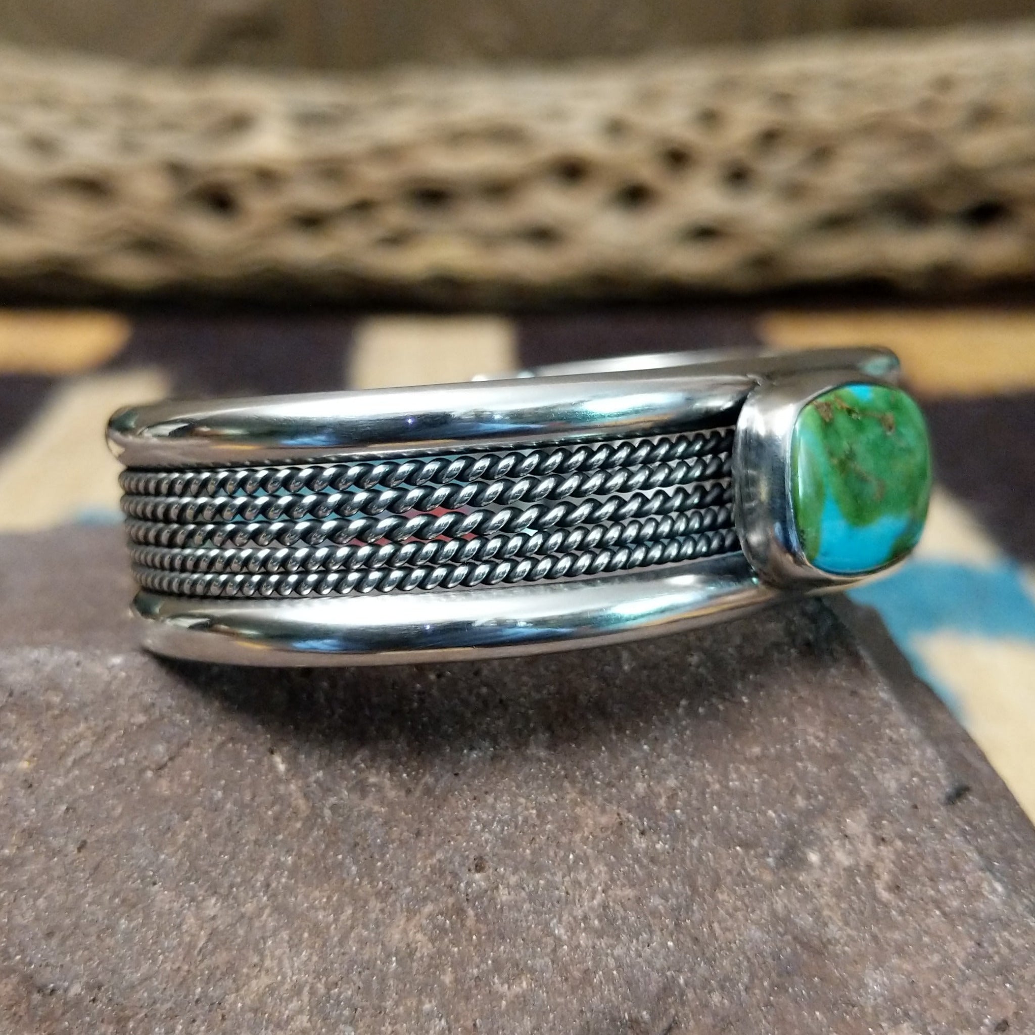 Navajo Sonoran Gold turquoise cuff by H.R.M. with a natural blue-green turquoise stone on a triple-shank sterling silver cuff; side view.