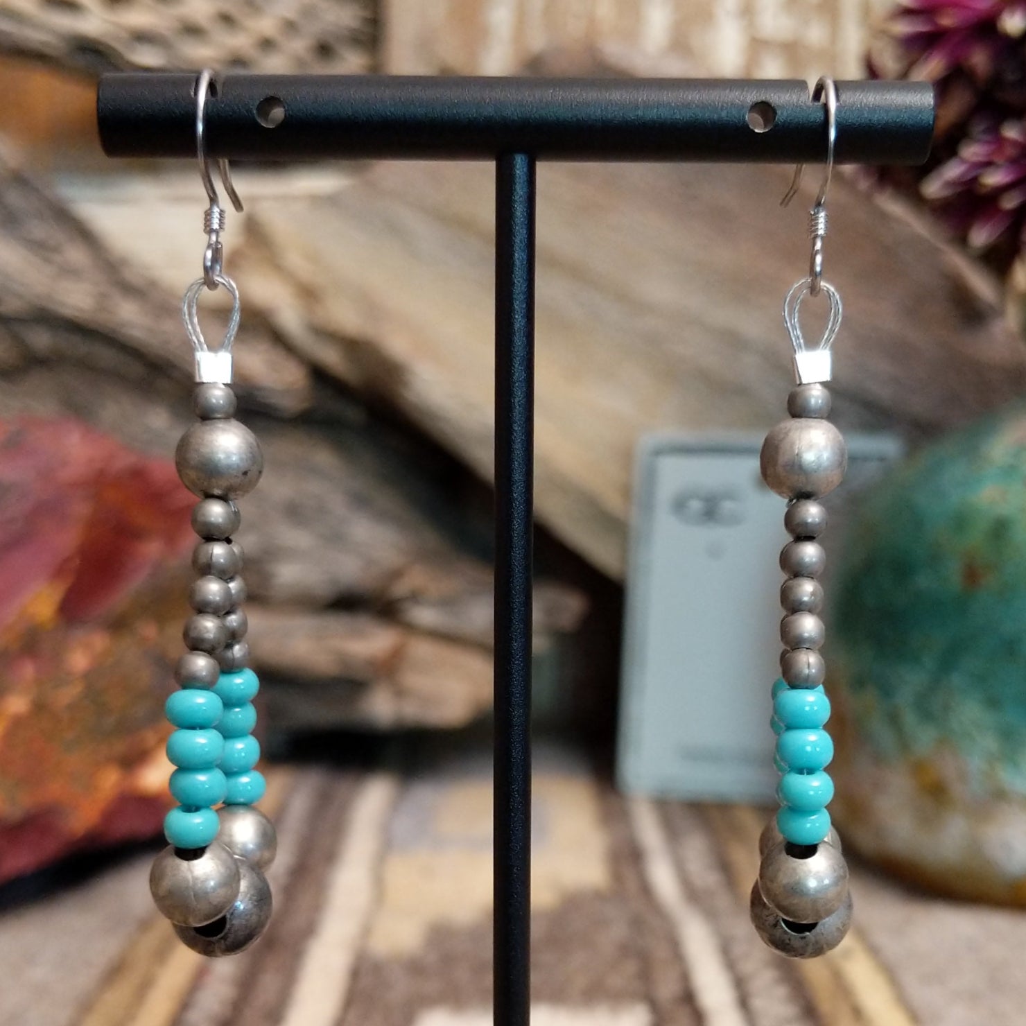 A pair of earrings in the shape of teardrops featuring silver and turquoise beads.