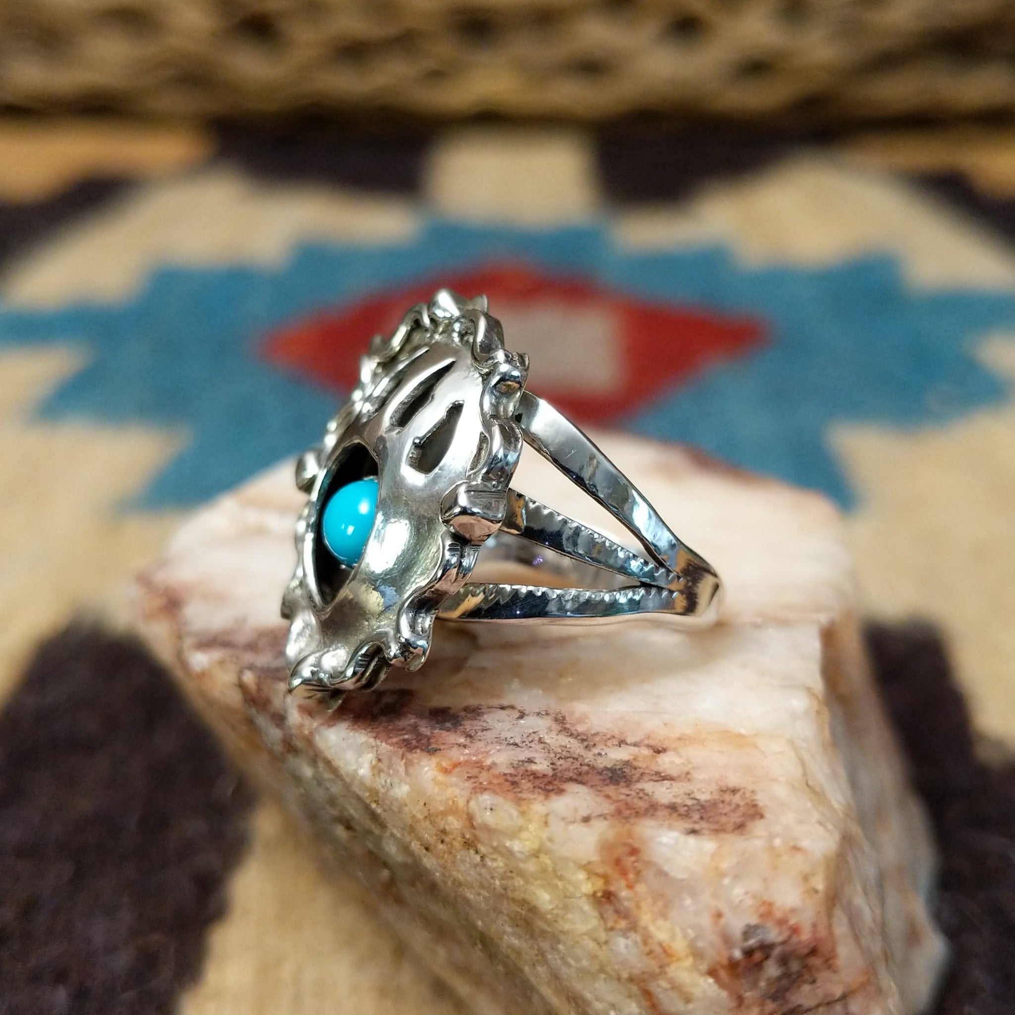 Navajo turquoise bear paw shadowbox ring, featuring a round blue turquoise stone set in a handcrafted sterling silver bear paw design with a dimensional shadowbox setting. Side view.
