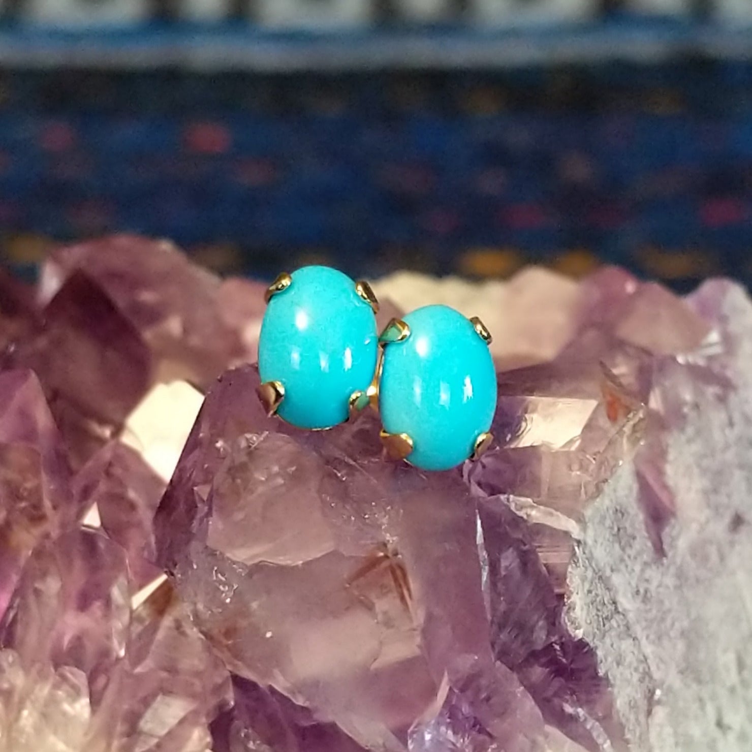 Two Navajo turquoise cabochon earrings with blue stones set in gold settings.