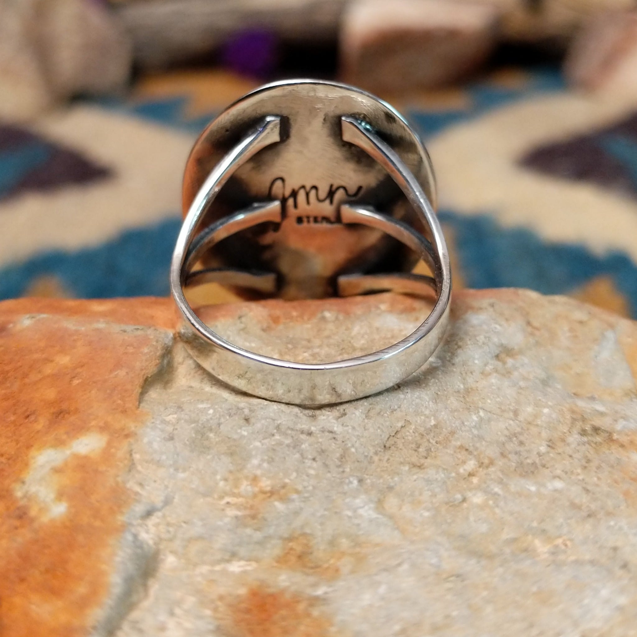 Sterling silver Navajo turquoise ring by J.M.N. with an oval sky-blue stone and hand-stamped horn design; underside view.