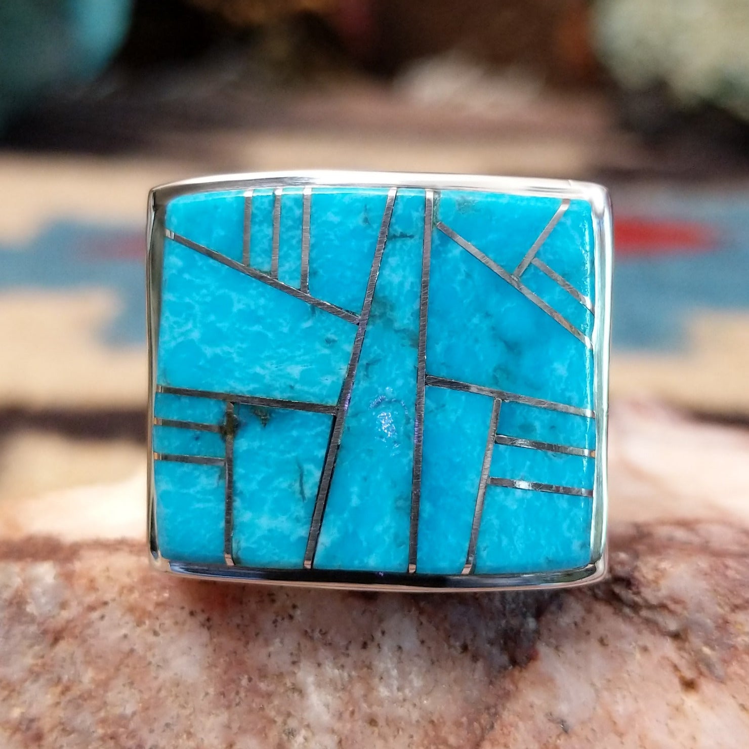 Sterling silver ring featuring a rectangular turquoise inlay and geometric channel work.