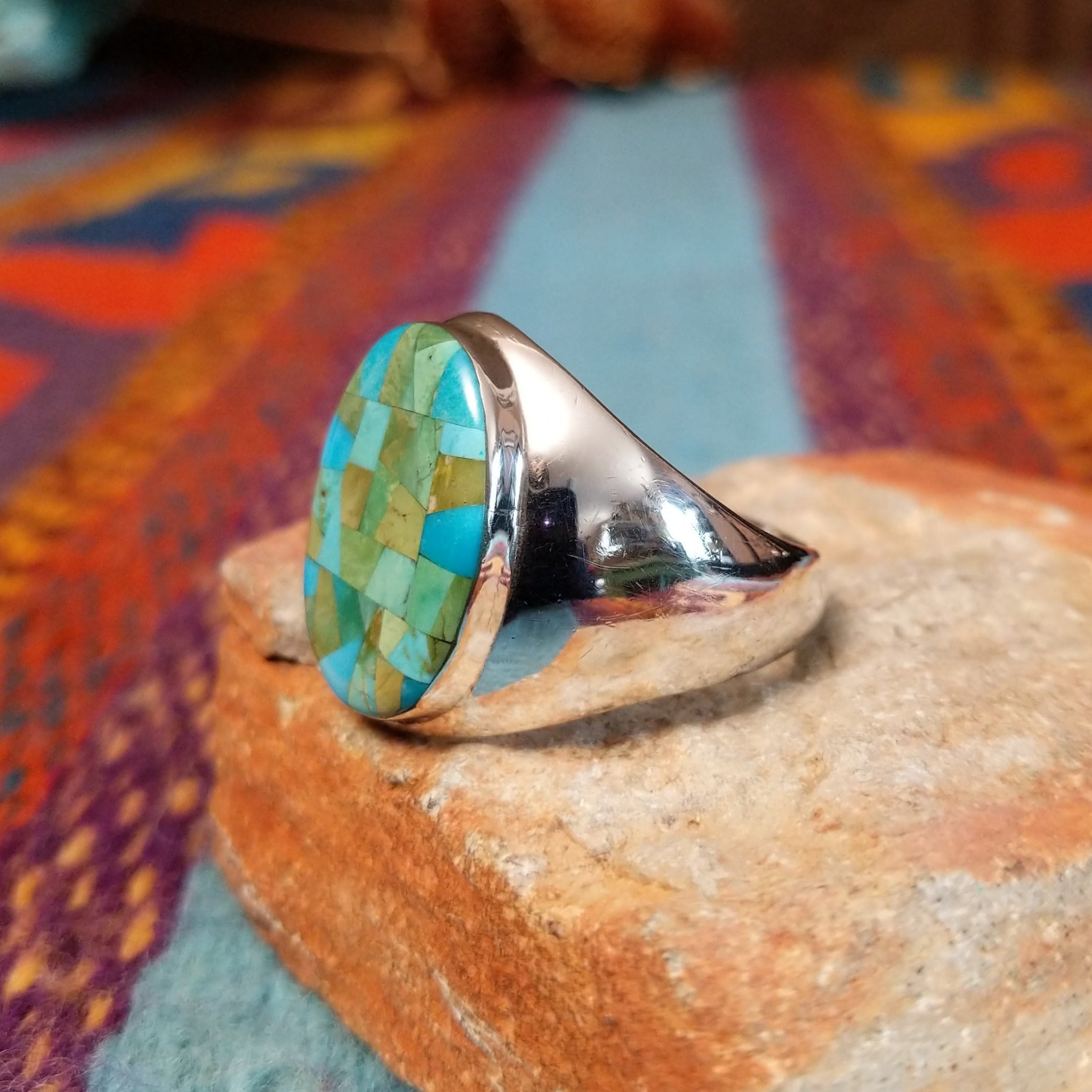 Navajo Turquoise Mosaic Ring featuring an oval face filled with geometric turquoise pieces in blue, aqua, sage, and green tones, set in a wide polished silver band; side view.