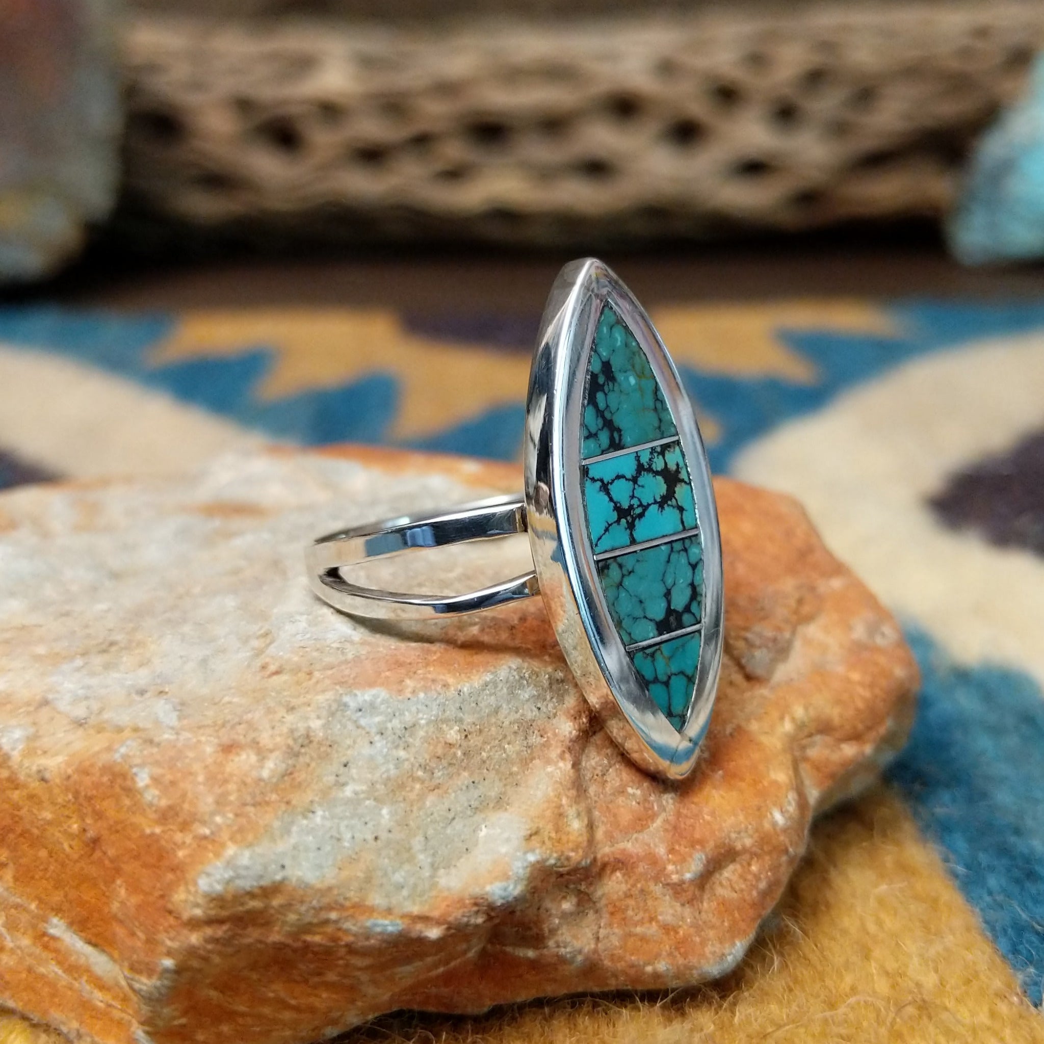 Handcrafted Navajo sterling silver navette ring featuring an elongated turquoise inlay with natural black matrix, set in a polished bezel with a split shank design; side view.