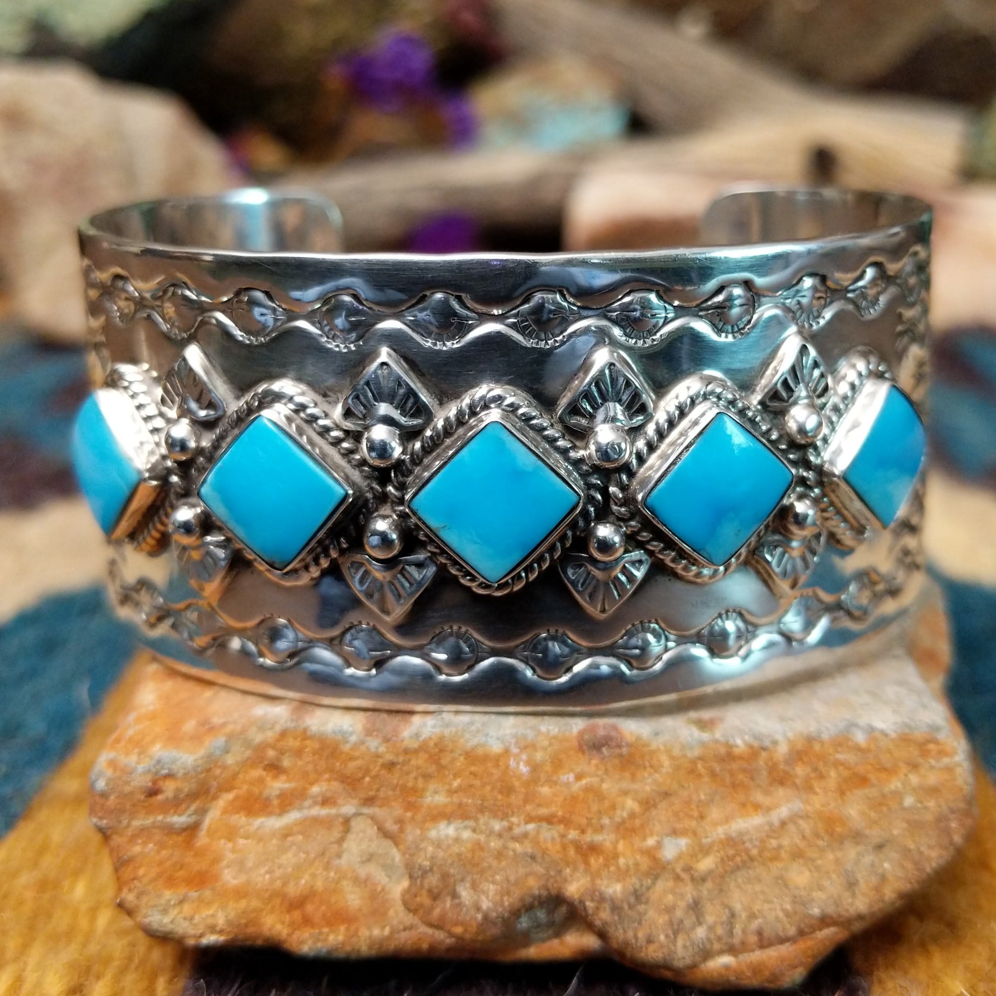 Handcrafted Navajo sterling silver cuff featuring five diamond-shaped turquoise stones in twisted rope bezels with intricate hand-stamped Southwestern designs and silver bead accents.