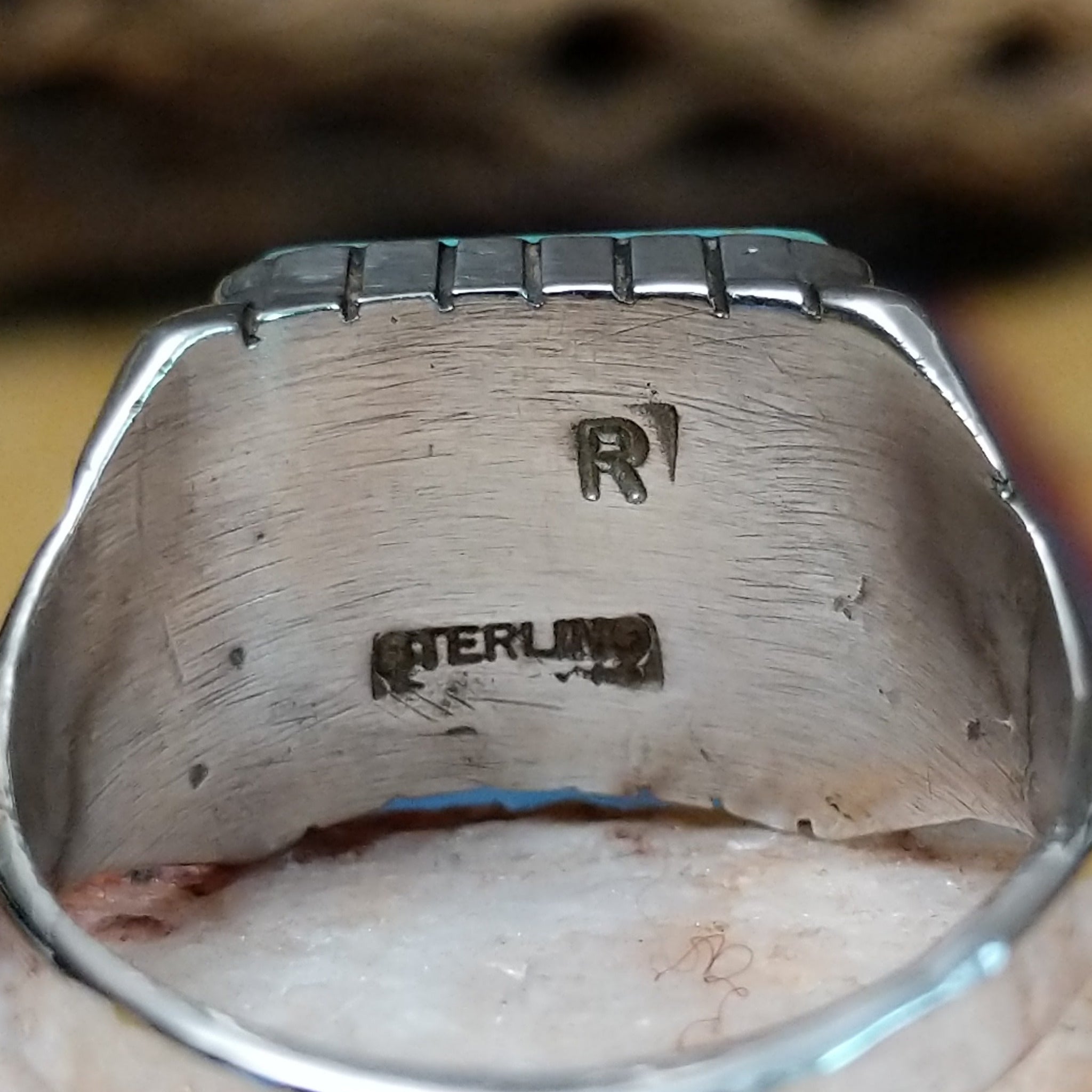 Navajo turquoise ring by R., featuring a square turquoise stone with natural blue and green tones set in a handcrafted sterling silver band with stepped side accents. Artisan and Sterling Silver stamp.