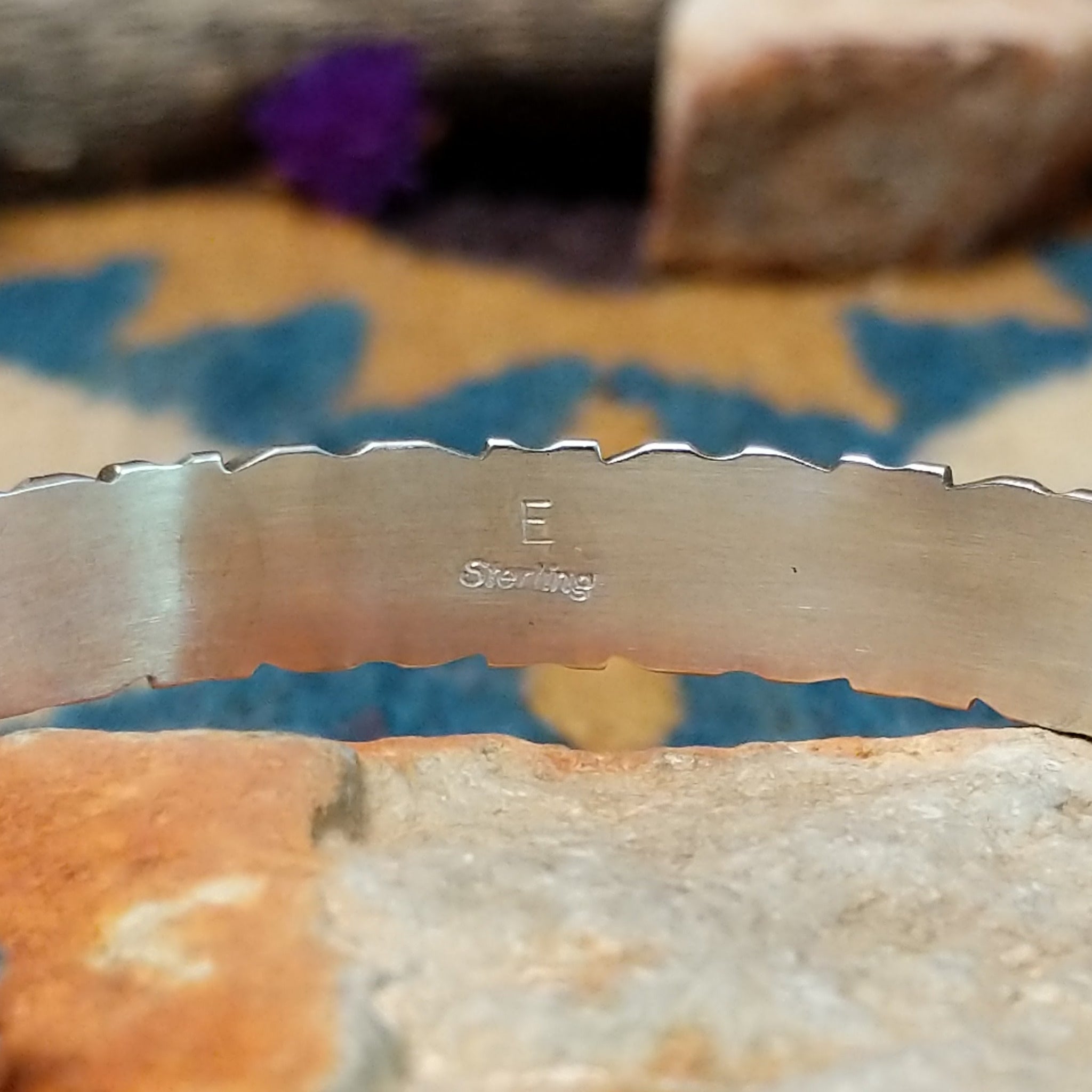 Handcrafted sterling silver Navajo cuff by E. featuring a vibrant row of turquoise channel inlay with a polished silver frame and scalloped edge detailing; artisan and Sterling Silver stamp.
