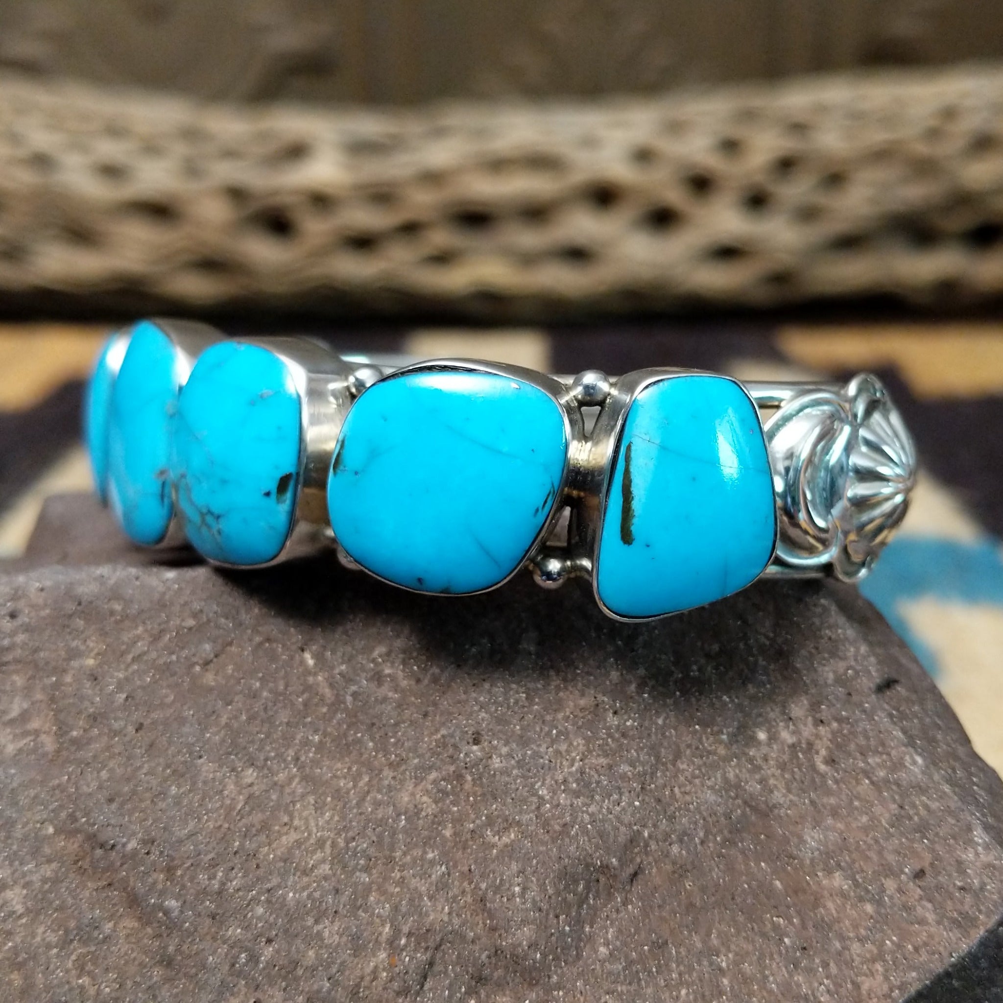 Navajo turquoise septet cuff, featuring seven blue turquoise stones with natural matrix set in a handcrafted sterling silver cuff; side view.