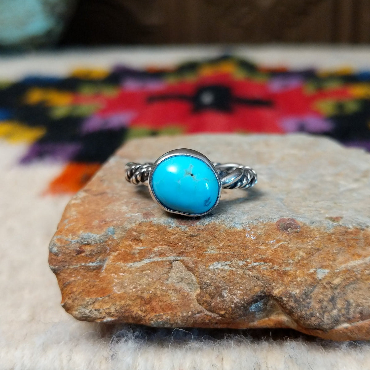 This graceful Navajo Twisting Turquoise Ring features a rounded sky-blue turquoise stone with subtle natural matrix, set in a smooth silver bezel on a twisted silver band.