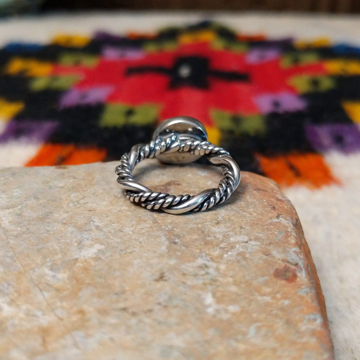 This graceful Navajo Twisting Turquoise Ring features a rounded sky-blue turquoise stone with subtle natural matrix, set in a smooth silver bezel on a twisted silver band; underside view.