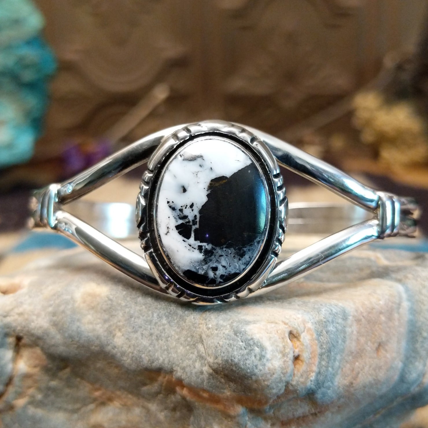 Sterling silver cuff bracelet with a white buffalo stone set in a round bezel, framed by incised lining and a layered band.