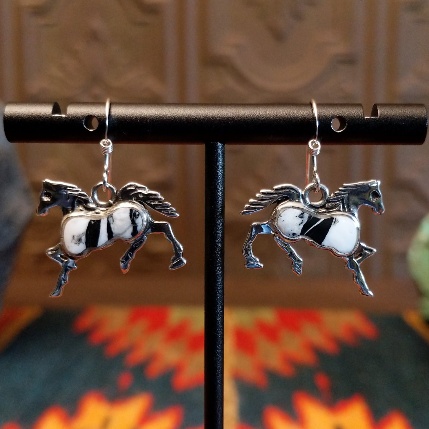 Sterling silver horse earrings with white buffalo stones set in the centers.