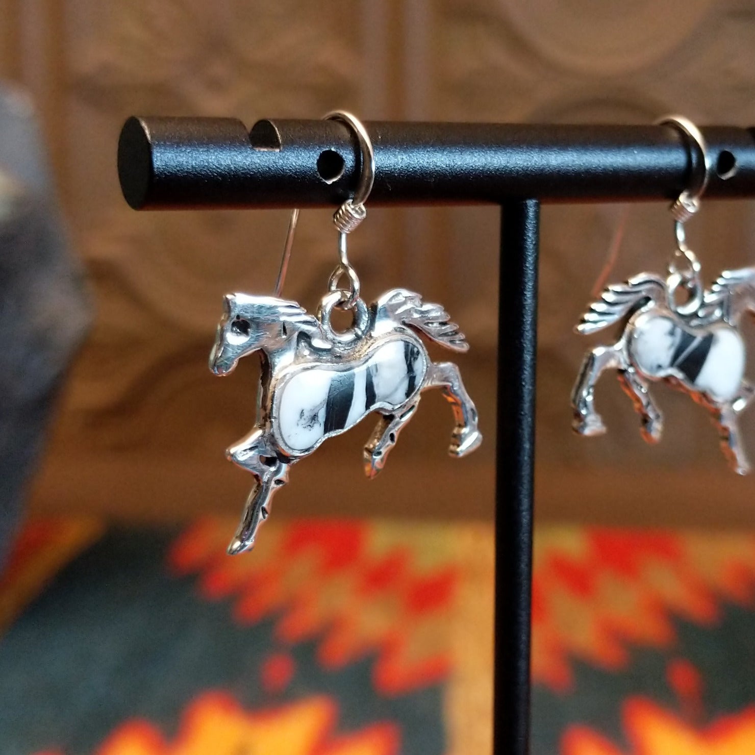Sterling silver horse earrings with white buffalo stones set in the centers.