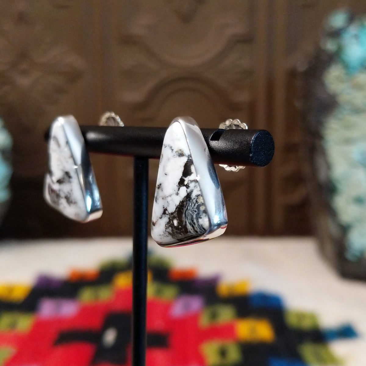 Navajo White Buffalo Triangle Earrings by L.P. featuring polished triangular white stones with natural black matrix patterns set in smooth silver bezels; side view.