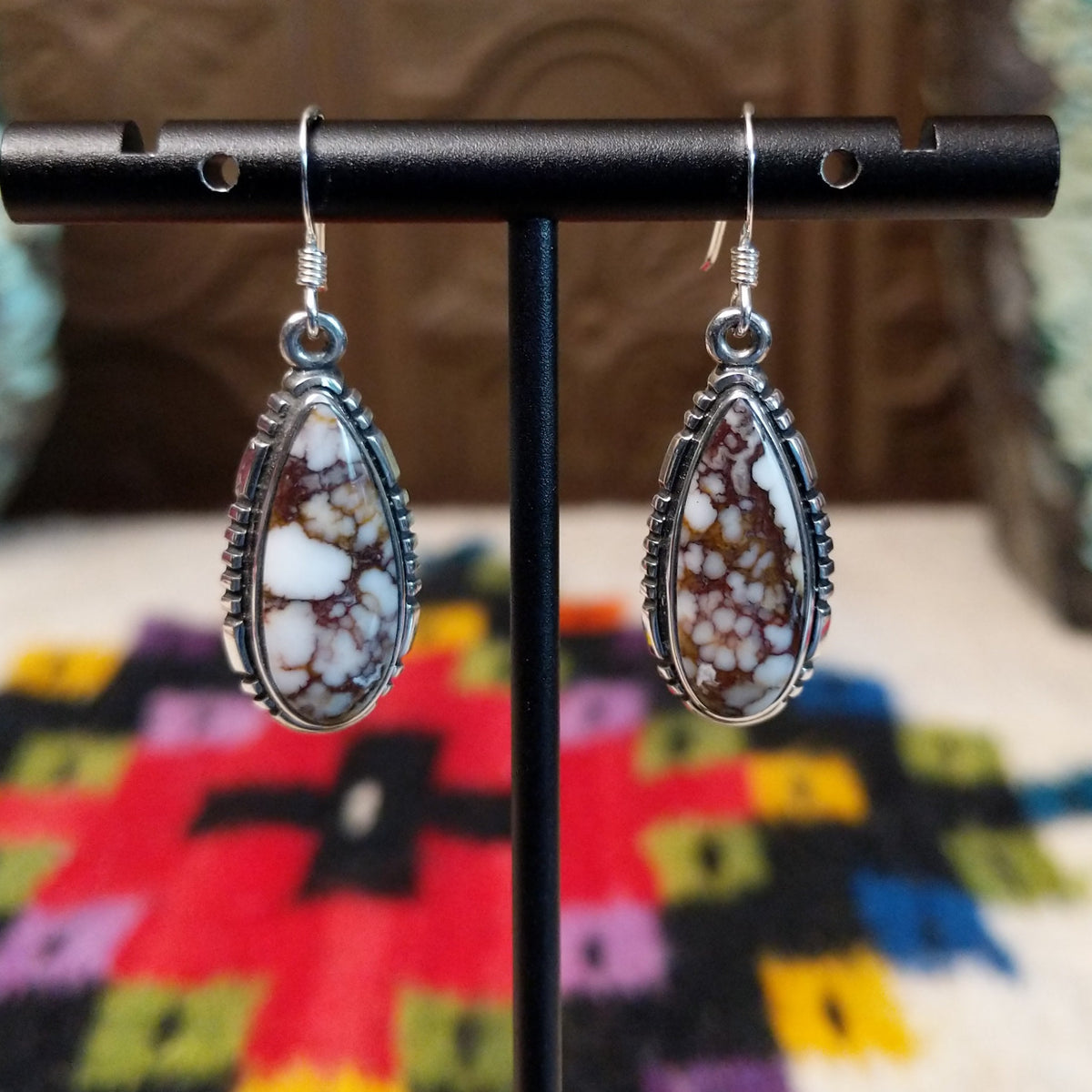 Navajo Wild Horse Teardrop Earrings by B.A. featuring polished white and reddish-brown matrix stones in detailed silver settings with French ear wires.