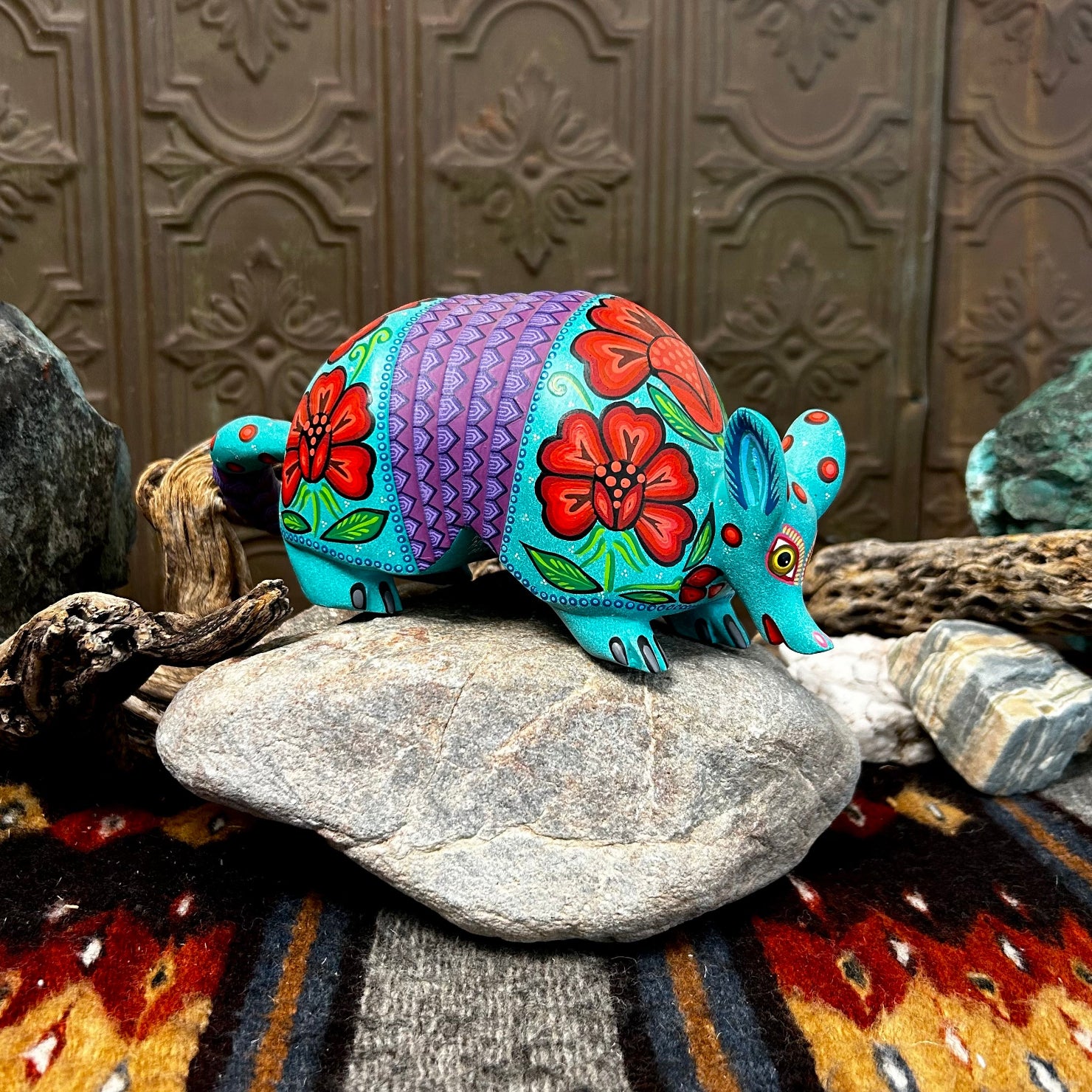 Armadillo figurine in bright teal with orange flowers, featuring small black eyes and yellow accents.