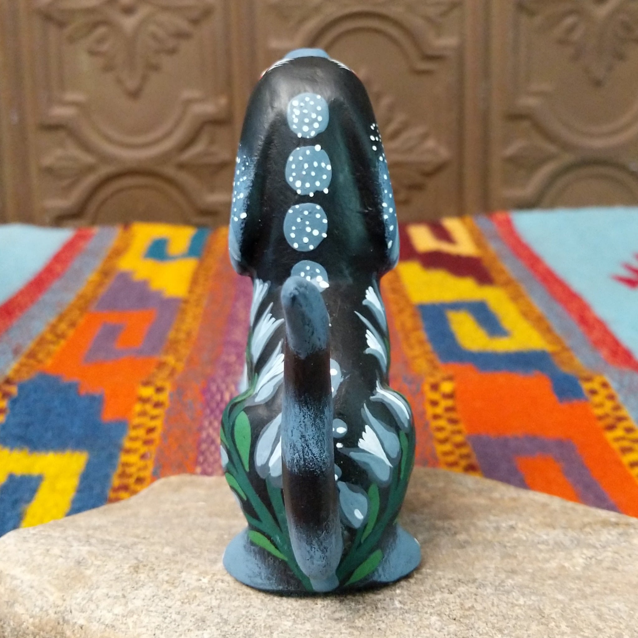 Oaxacan dog wood carving by Jose Olivera Perez with an open mouth, raised curved tail, and hand-painted floral and leafy designs.